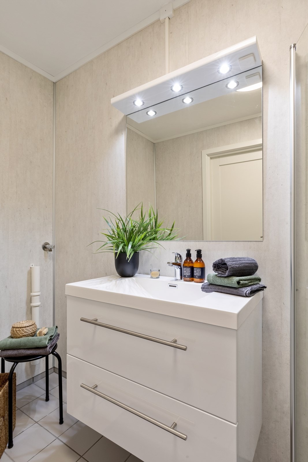 Servantinnredning i hvitt og opplegg for vaskemaskin på badet Galleribilde