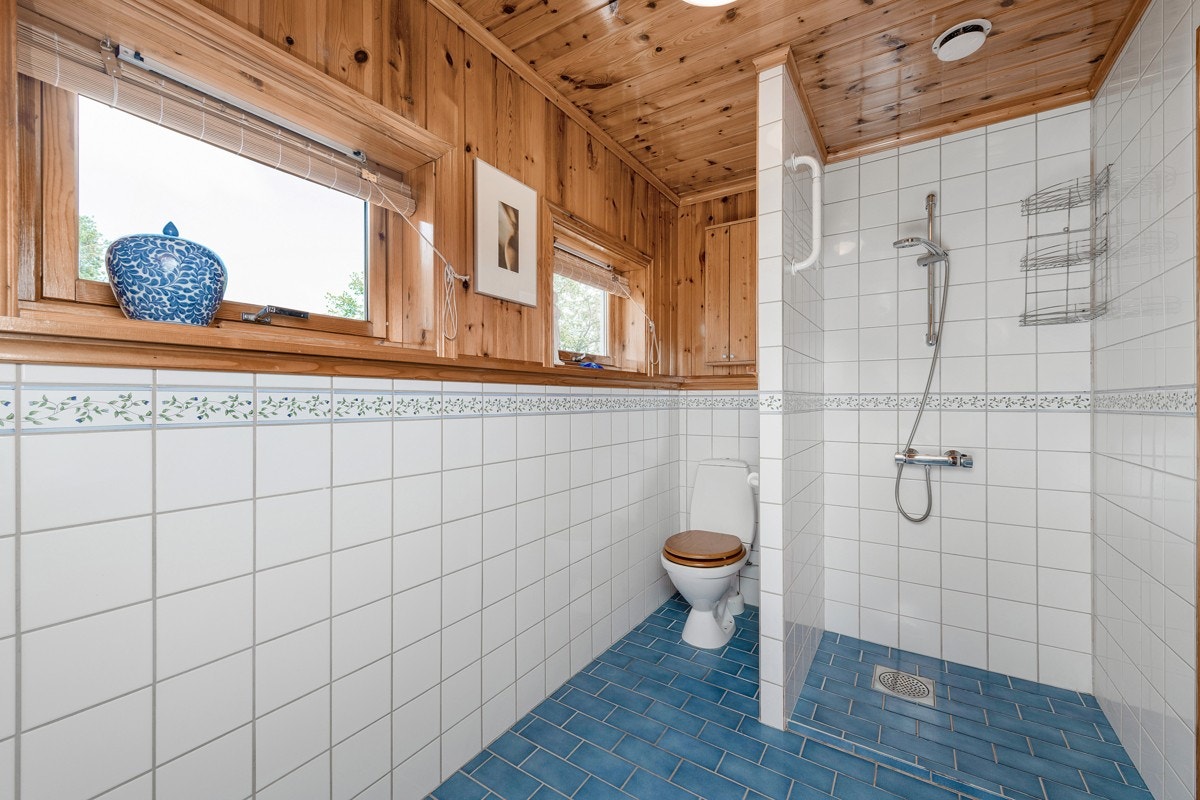 Badet ligger i andre etasje, har blå gulvfliser med underliggende varme, hvite fliser med dekorbord opp til brystning, og panelte flater for øvrig. Galleribilde