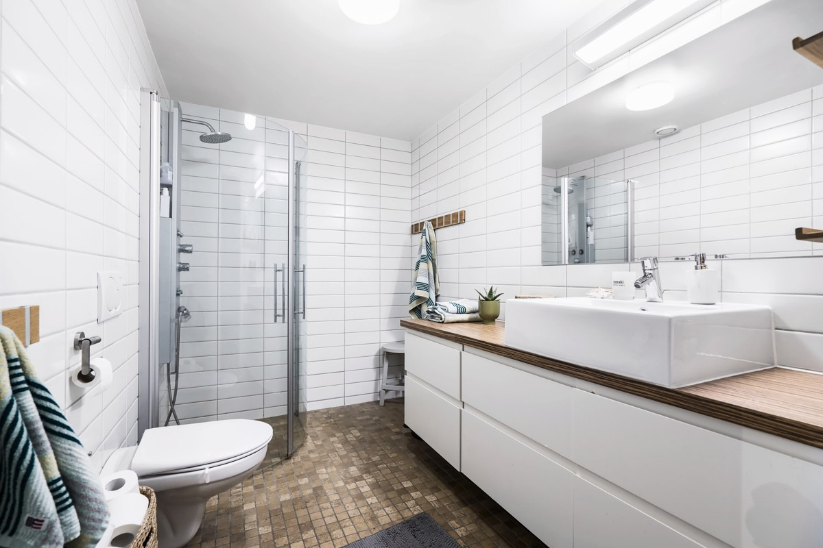Badet er komplett fliselagt med vegghengt toalett, dusjhjørne og moderne baderomsinnredning