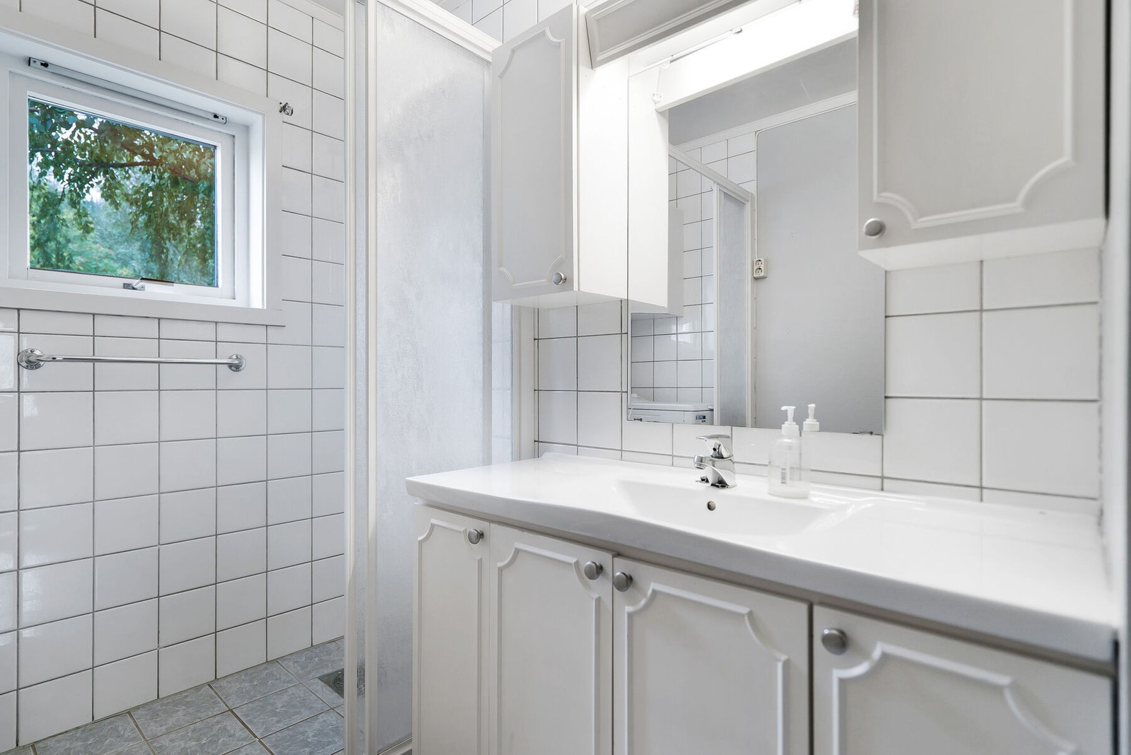 Badet er helfliset med en opphøyd dusjsone og opplegg for vaskemaskin i dusjnisje. Galleribilde