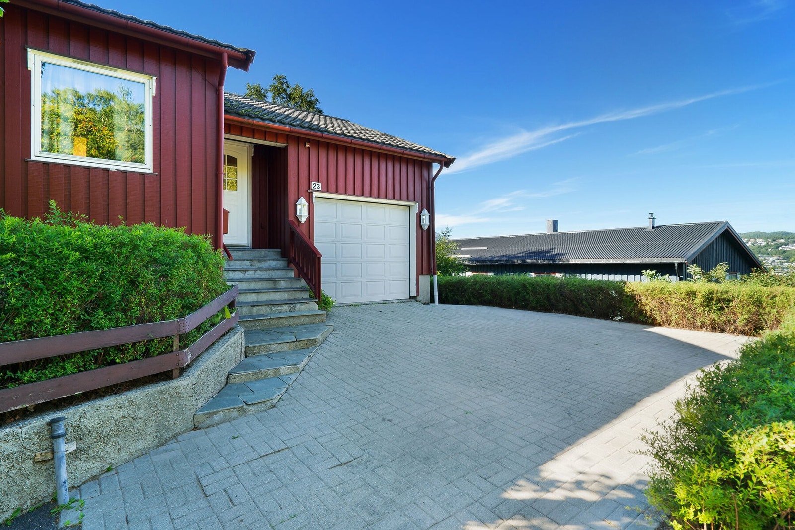 Eiendommen har både carport, oppstillingsplasser og garasje med elektrisk portåpner. Brosteinsbelagt innkjørsel og en liten sti på ca. 46m² gir et godt førsteinntrykk. Galleribilde