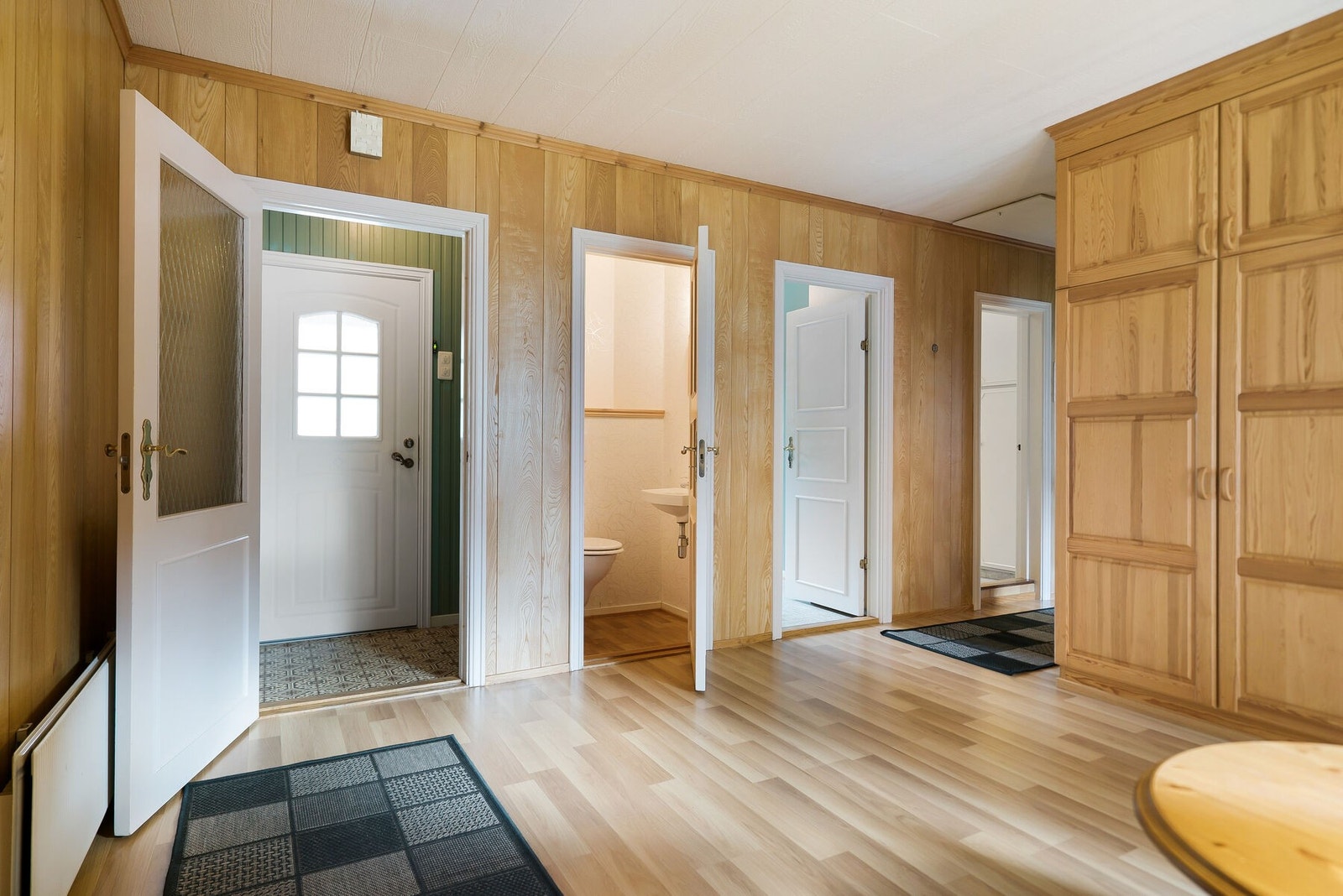 Entréen var opprinnelig tenkt noe mindre enn den er utført i dag. Der garderobeplassen er til høyre var det tegnet inn et soverom. Ettersom behovet ikke var helt tilstede ble dette tatt bort, men kan enkelt settes opp igjen. Galleribilde