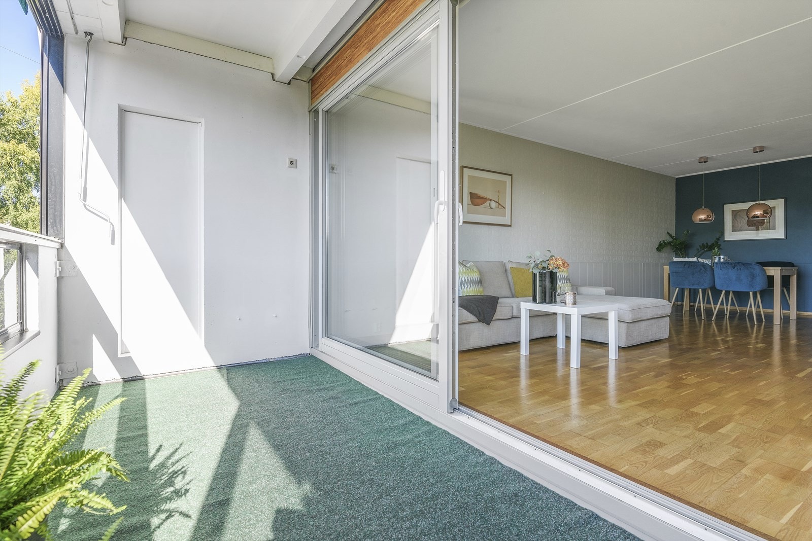 Stor skyvedør i glass åpner opp mot en innglasset balkong som blir som en forlengelse av boligen på sommerhalvåret Galleribilde