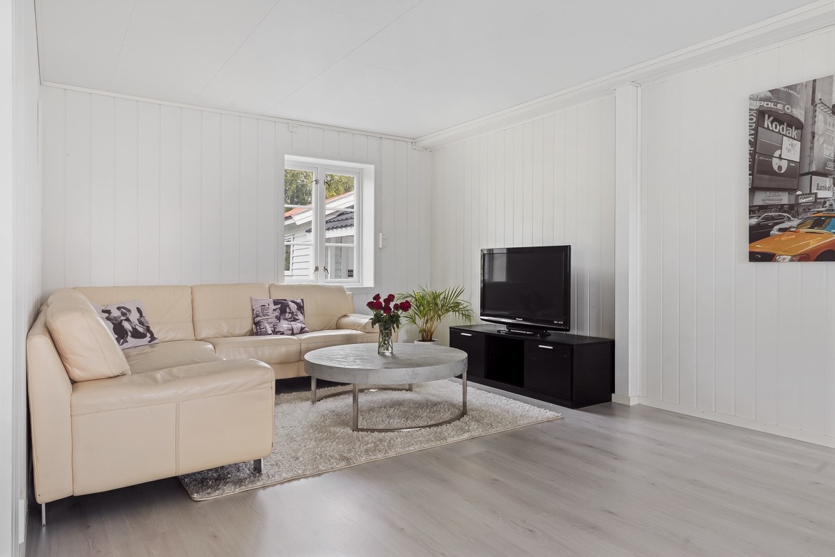 Lys og romslig stue med et lite teknisk rom bak sofaen. Hybel/utleiedel er innredet bak stuen. Denne var tidligere en del av bla. stue. Galleribilde
