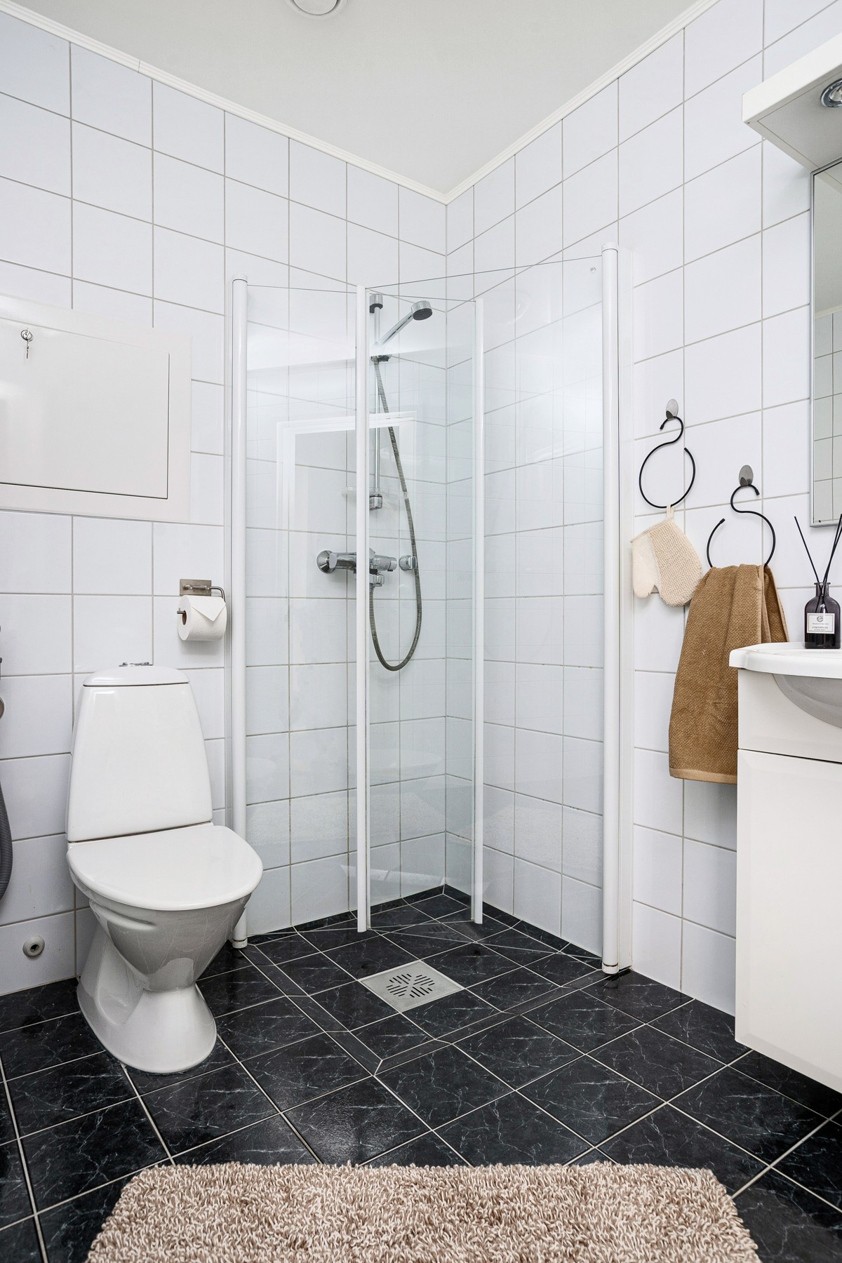 På badet er det dusjhjørne, wc og servant med speil