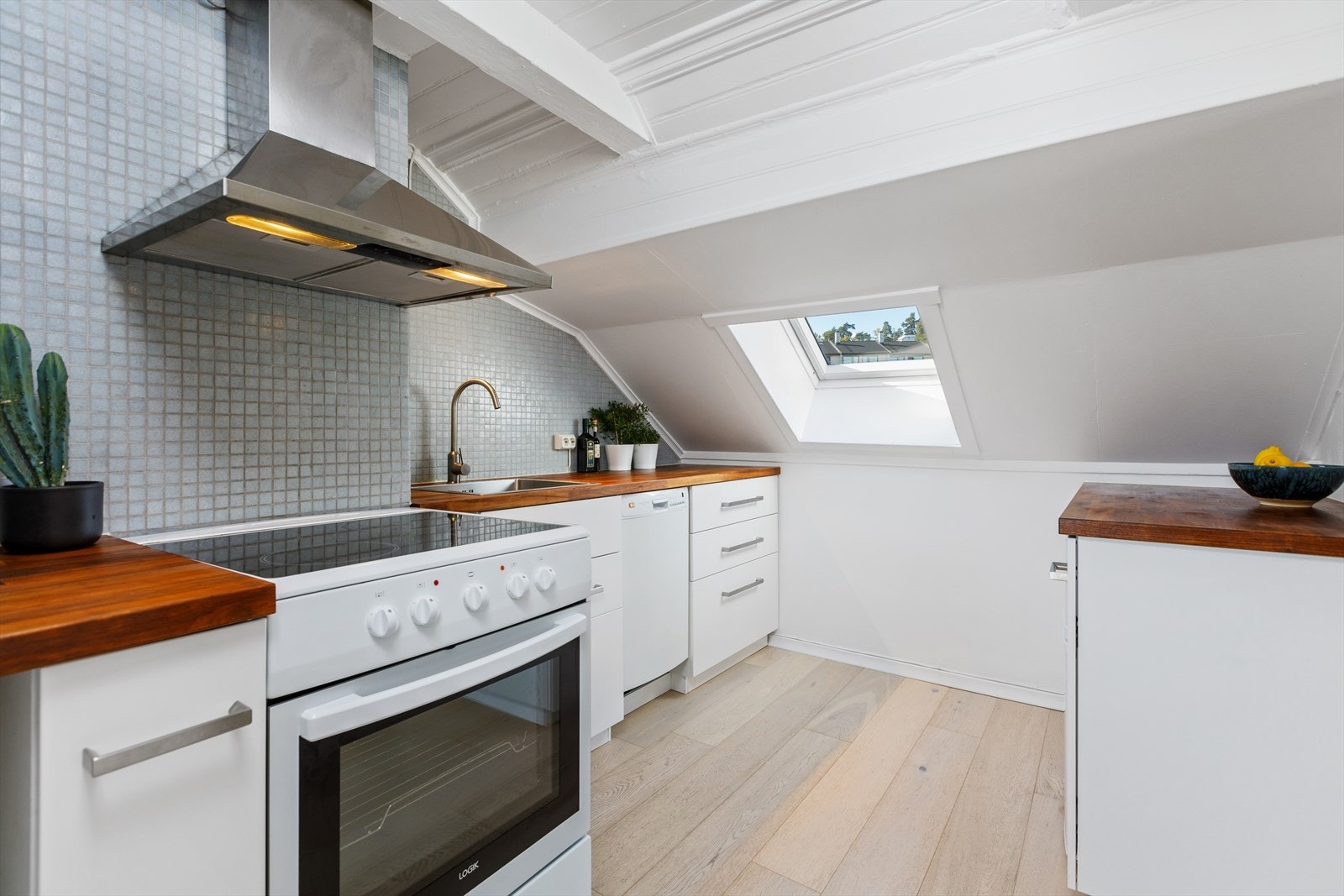 Pent kjøkken med tidsmessig innredning med hvite fronter og heltre benkeplate. Galleribilde