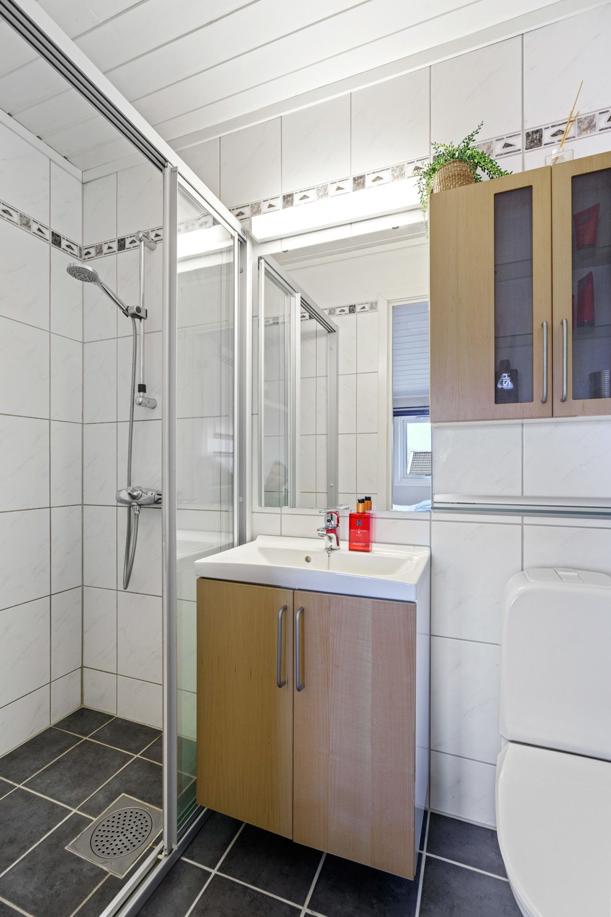Badet i 2.etasje er komplett flislagt med gulvvarme - her er det dusjnisje med skyvedører, heldekkende servant og toalett
