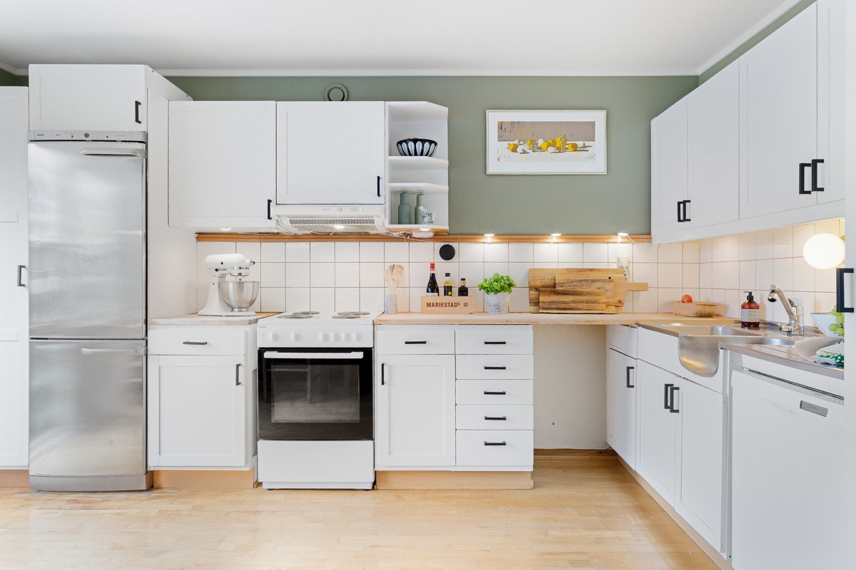 Kjøkkenet består av innredning fra IKEA med hvite profilerte fronter, benkeplate i heltre, nedsenket oppvaskkum. Galleribilde