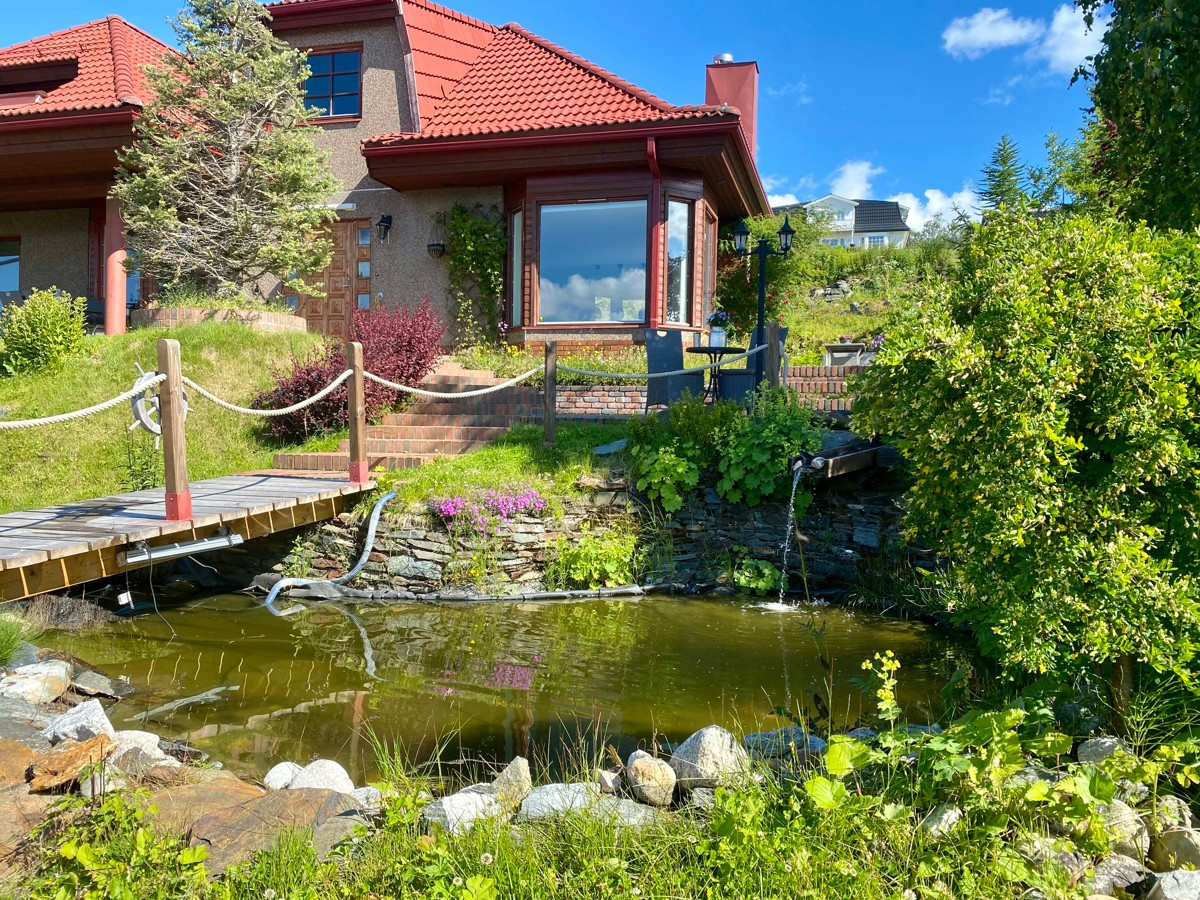 Tomten er pent opparbeidet med dam, plen og blomster