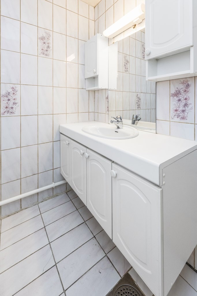 Den hvite innredningen har profilerte fronter, servant nedfelt i benkeplate, to veggskap, samt stort speil med lysarmatur og stikkontakt i overkant. Galleribilde