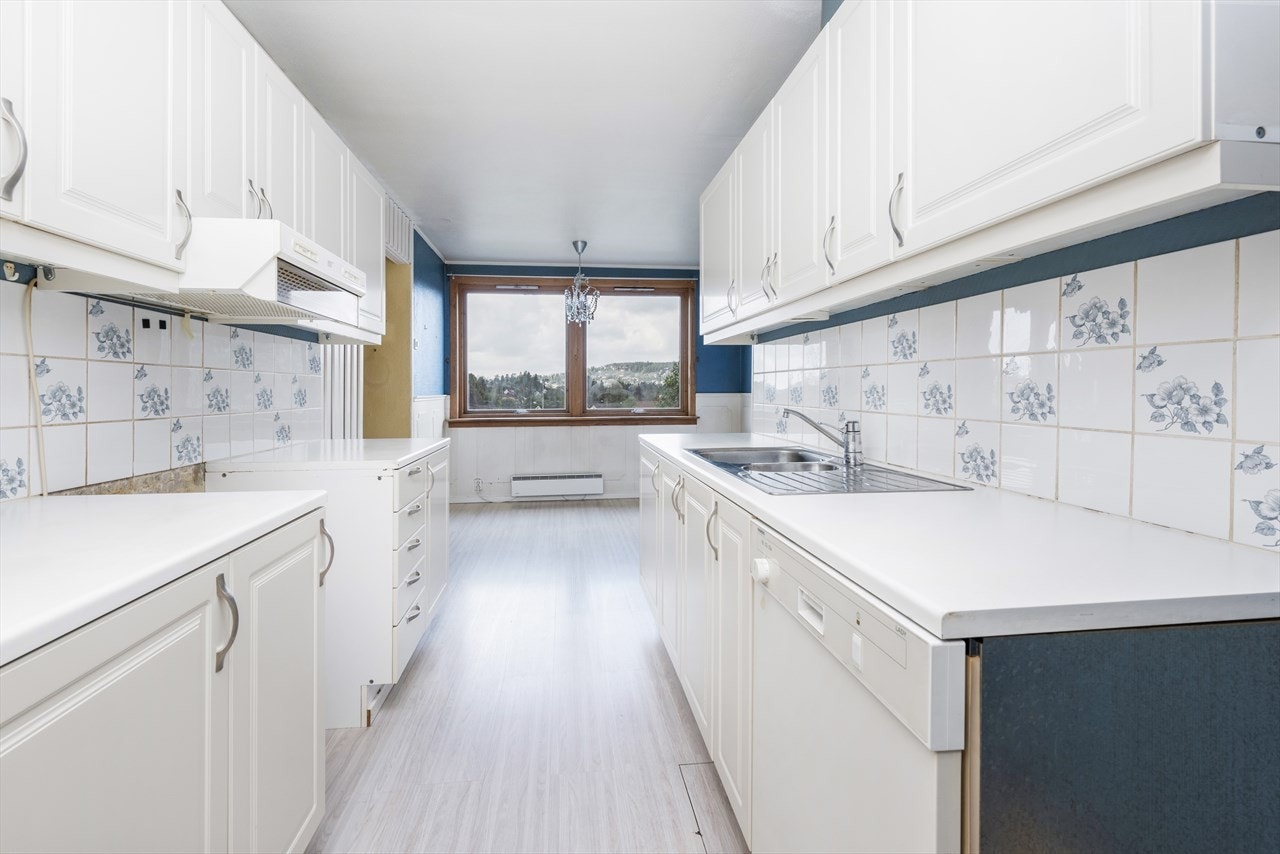 Kjøkkenet har laminatgulv, blåmalte vegger med hvitt brystningspanel, og tilknyttet spisestue med plass for stort spisebord. Galleribilde