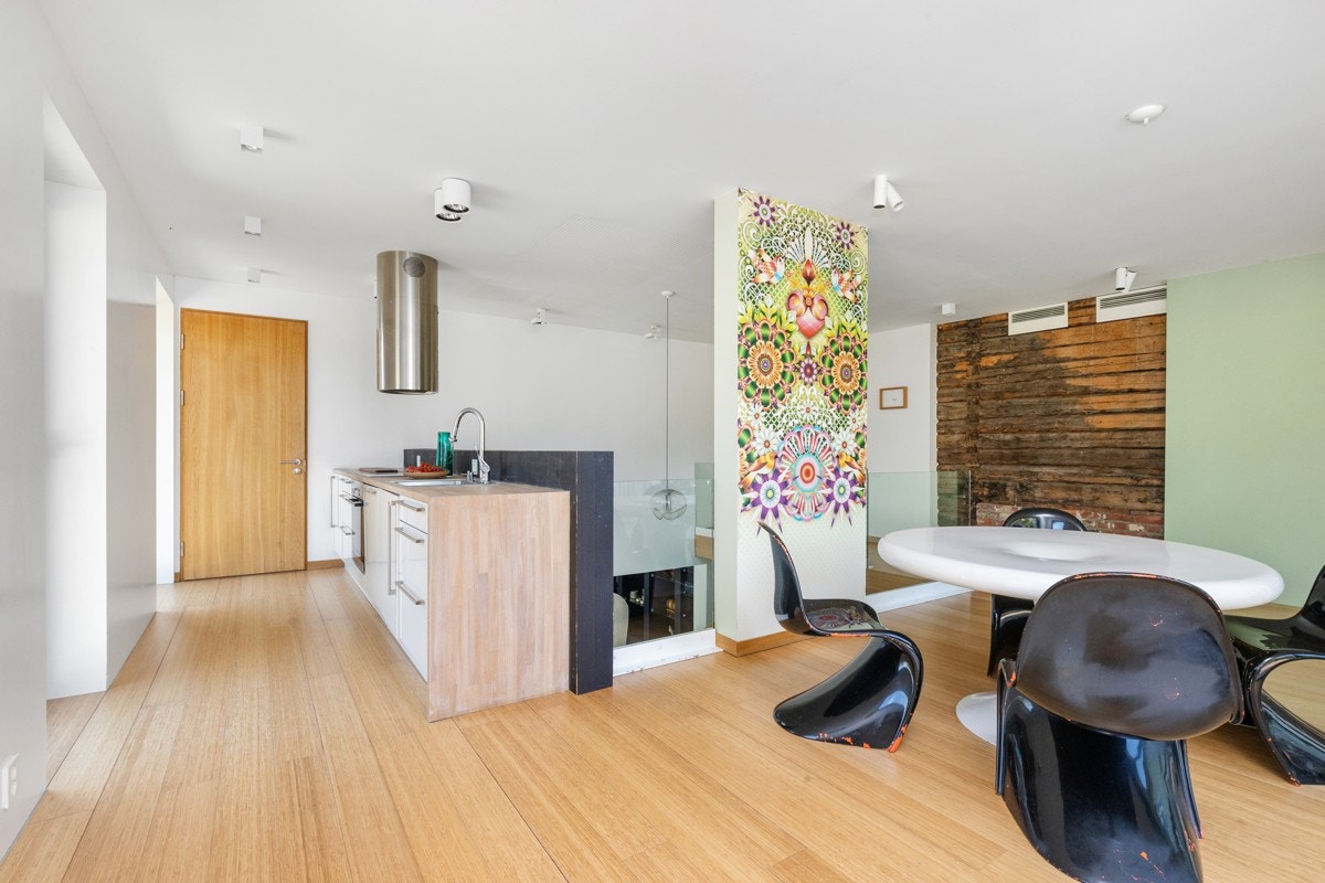 Kjøkken med spiseplass. Glassgelender ned mot underetasjen. Kjøkkeninnredningen har hvite fronter og heltre benkeplater. Integrert komfyr og koketopp, samt takhengt rustfri avtrekksventilator. Galleribilde