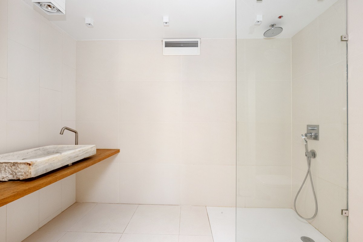 Flislagt bad i lyse farger med heltre benkeplate og en spansk marmorvask fra 1900-tallet. Badet har dusjnisje med takdusj, glassvegg og Corian gulv, samt veggehengt toalett. Galleribilde