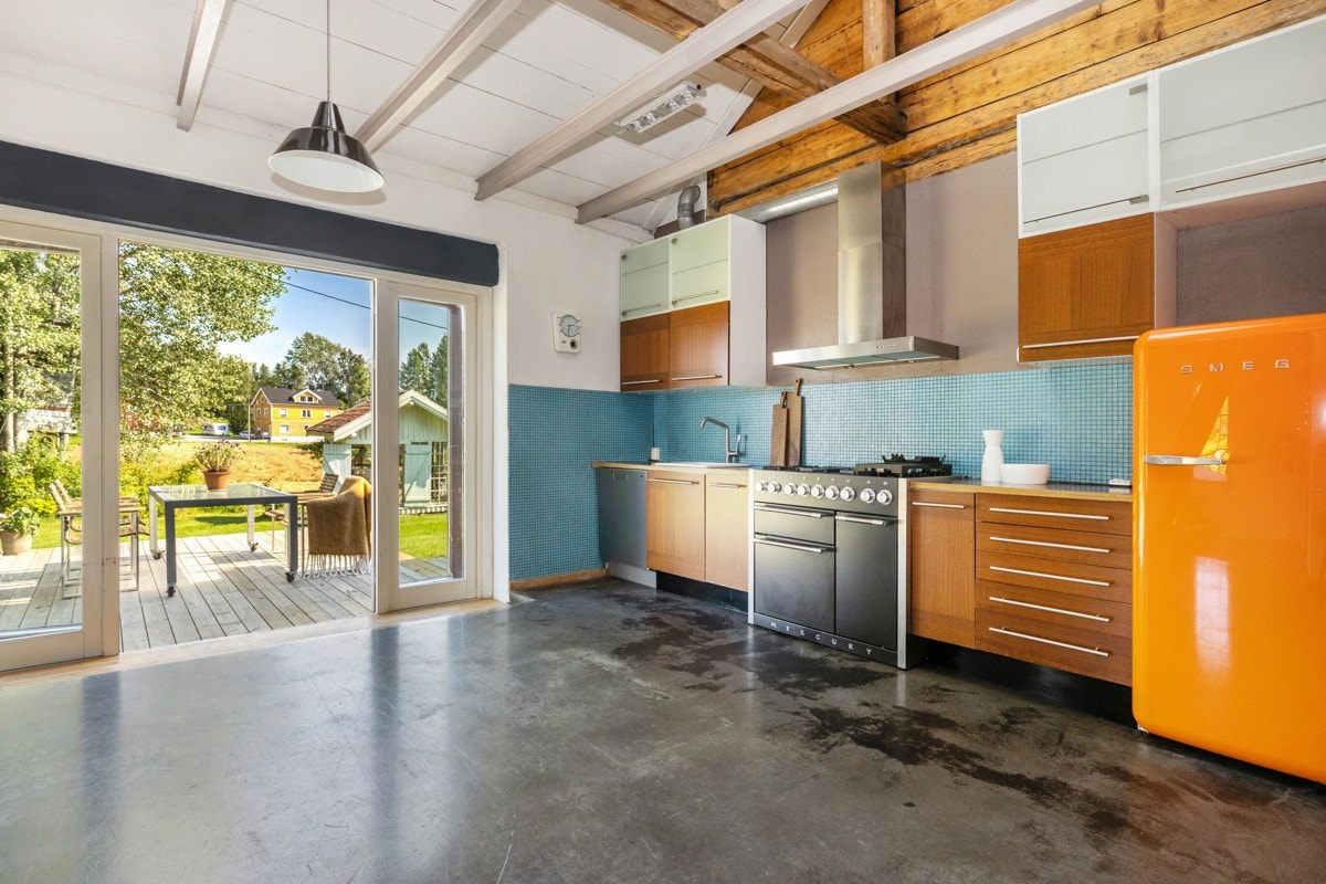 Kjøkkenet har mørke trefargede fronter som passer godt til de mørke benkeplatene og lyse fliser over benk som gir en fin kontrast. Galleribilde