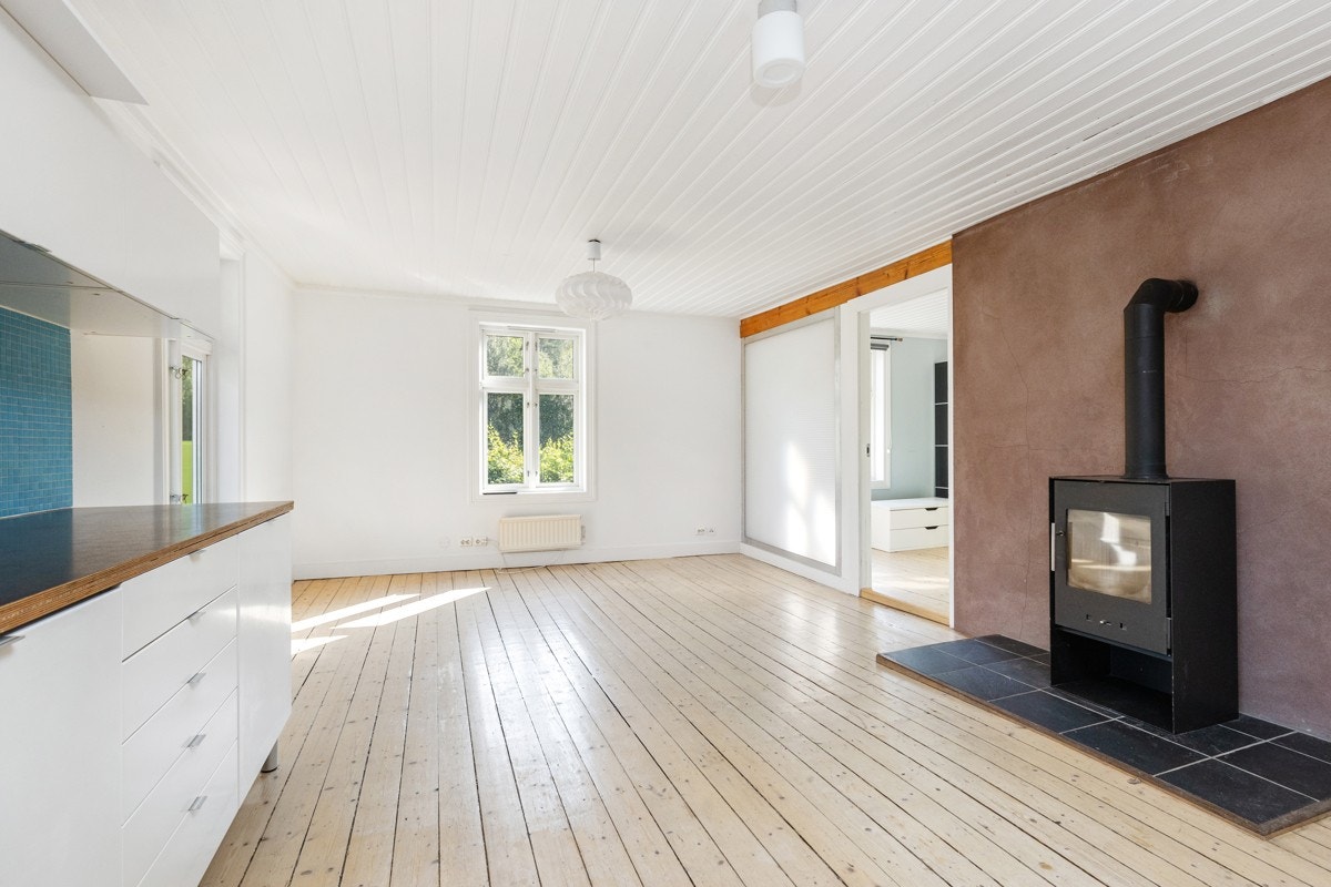 Lys kjøkkeninnredning med benkeplate og fliser over den ene benkeplaten. Integrert komfyr og koketopp. Galleribilde