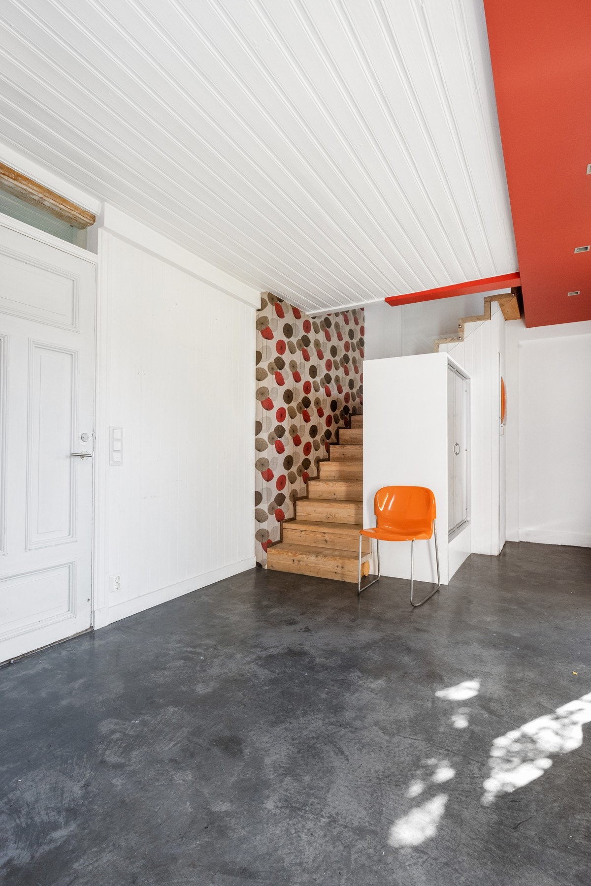 En stor hall som har spredt belysning med downlights i rød himling. Det er montert garderobe for klesoppbevaring. Galleribilde