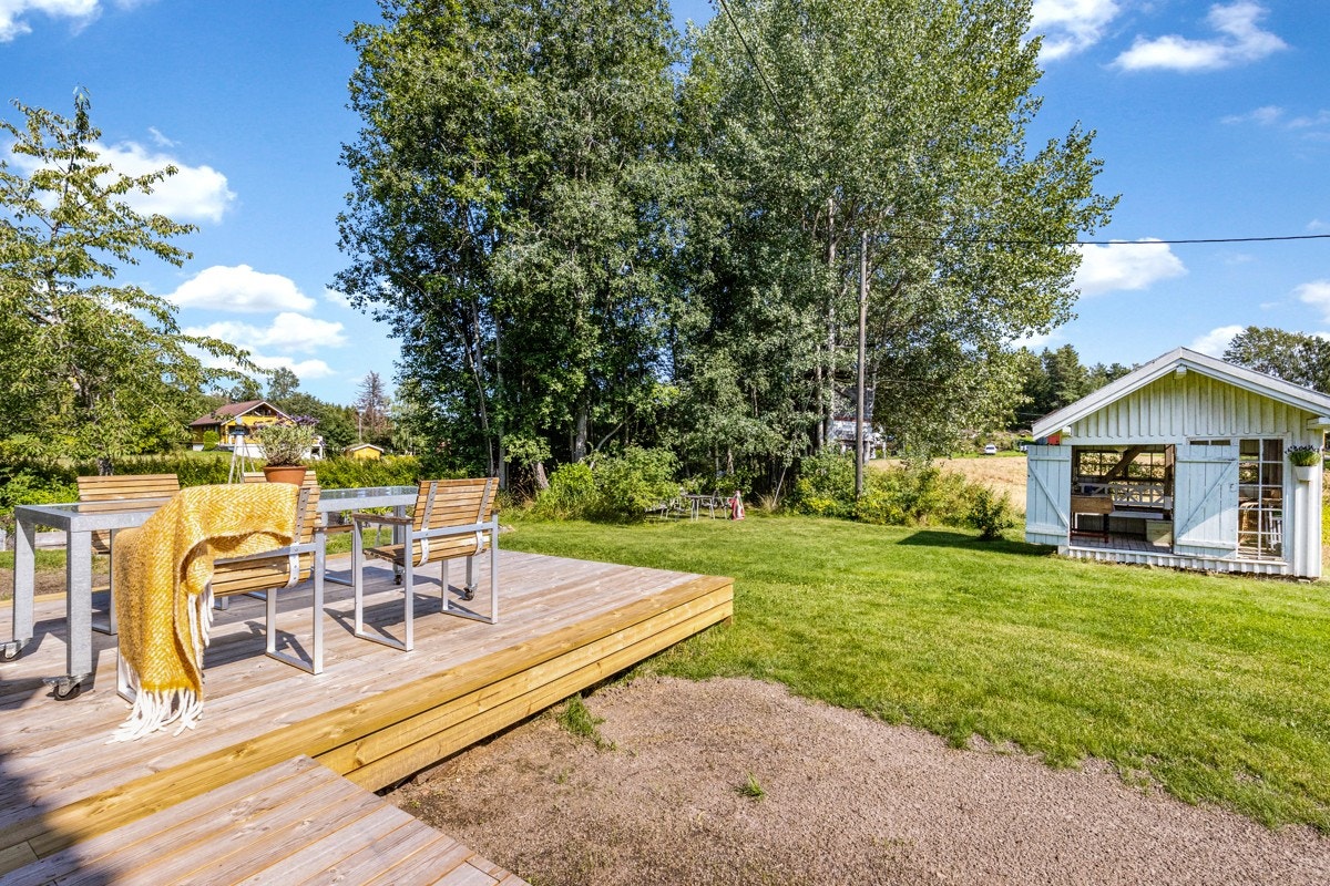 Lund med trær bevart og det er laget en hyggelig uteplass med benk og hengekøye. Galleribilde