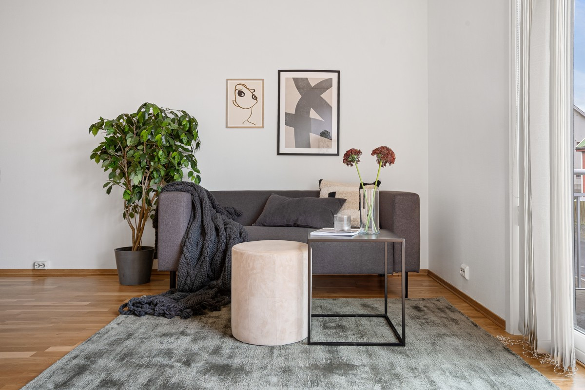 Leiligheten har en romslig stue i moderne stil, med parkettgulv og lyse vegger