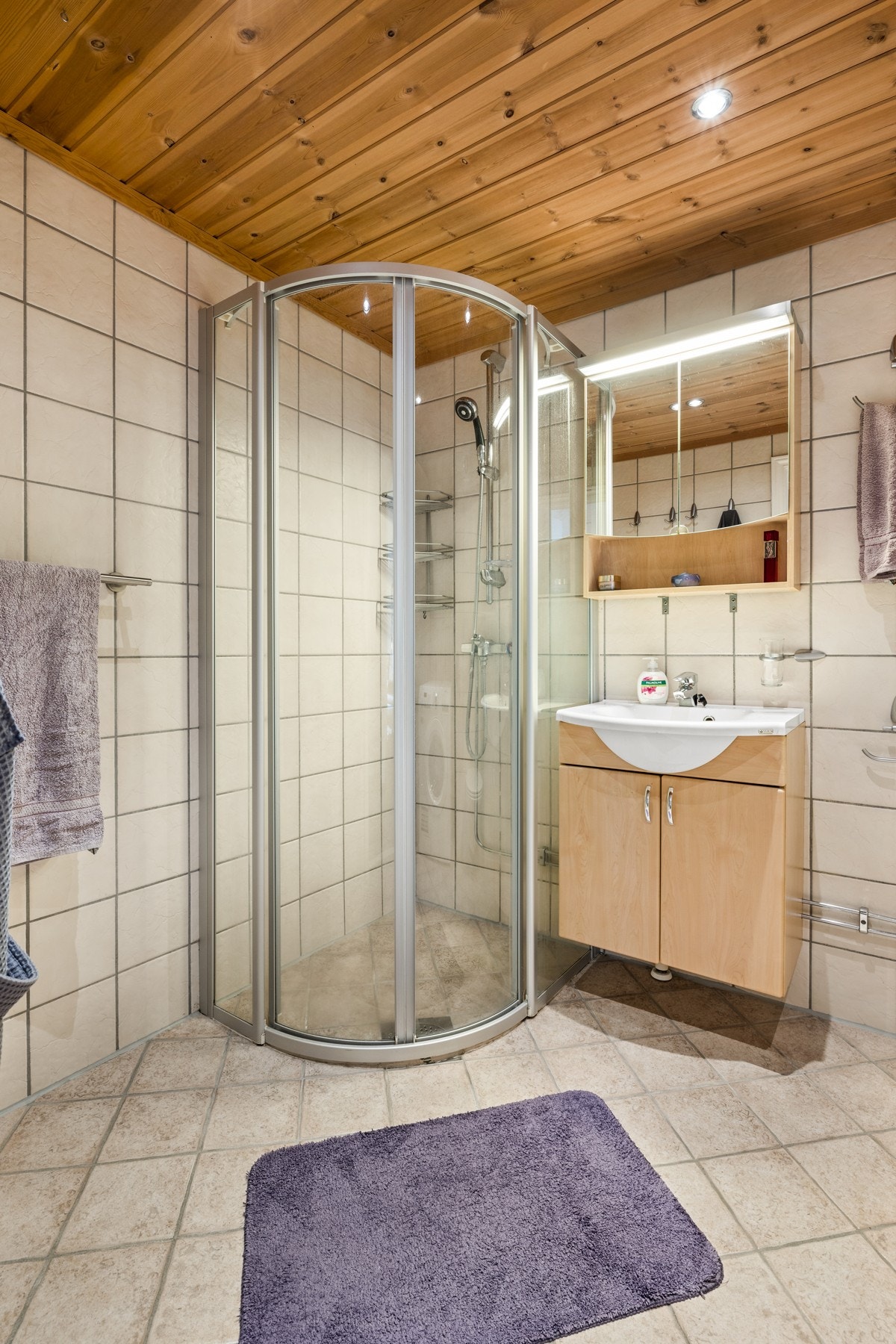 Baderommet har i tillegg downlights i himling og innredning bestående av blant annet dusjhjørne med skyvedør, vegghengt klosett, servant med underskap, speilskap med overlys og veggskap. Galleribilde