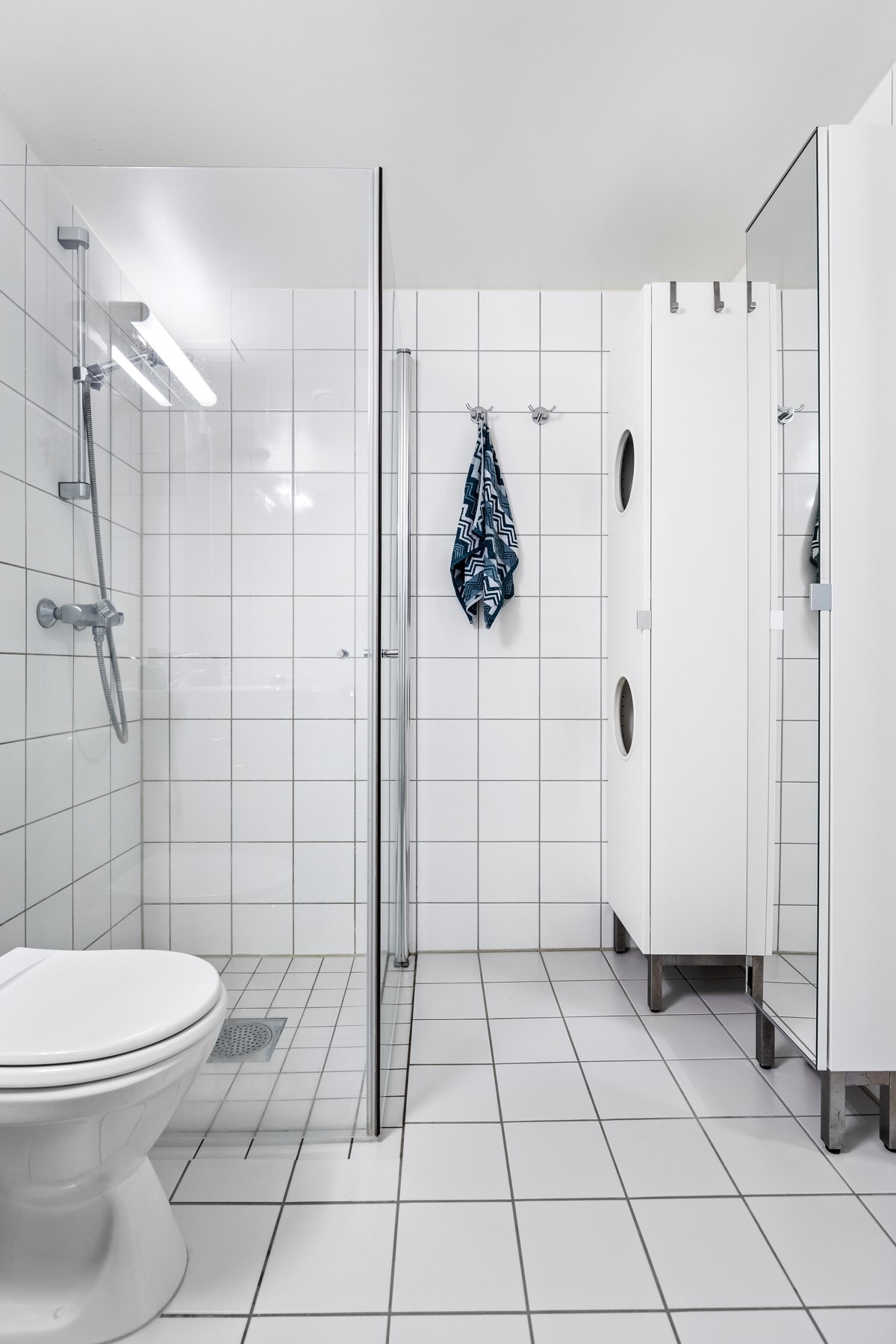 Pent flislagt bad med varmekabler i gulvet og opplegg for vaskesøyle - Innglasset dusjhjørne med foldedører Galleribilde