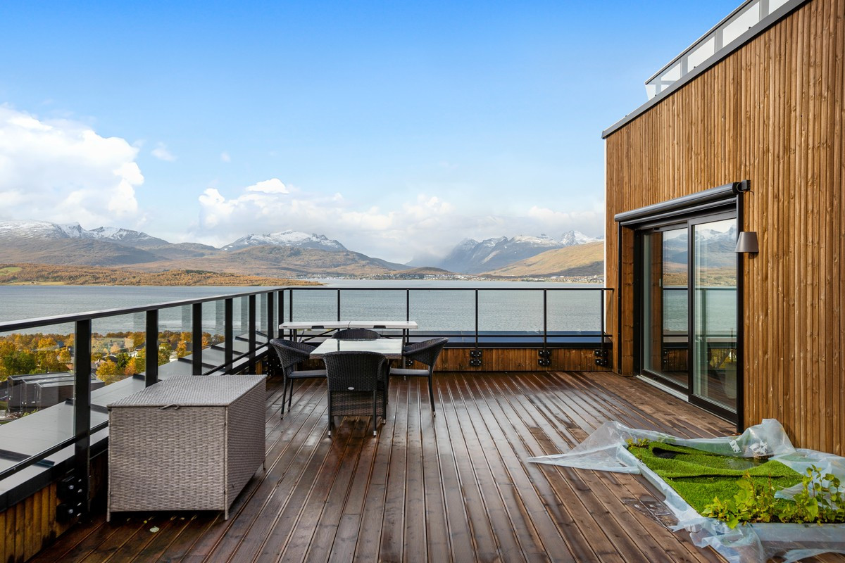 Takterrasse med nydelig utsikt over hav og mektige fjell