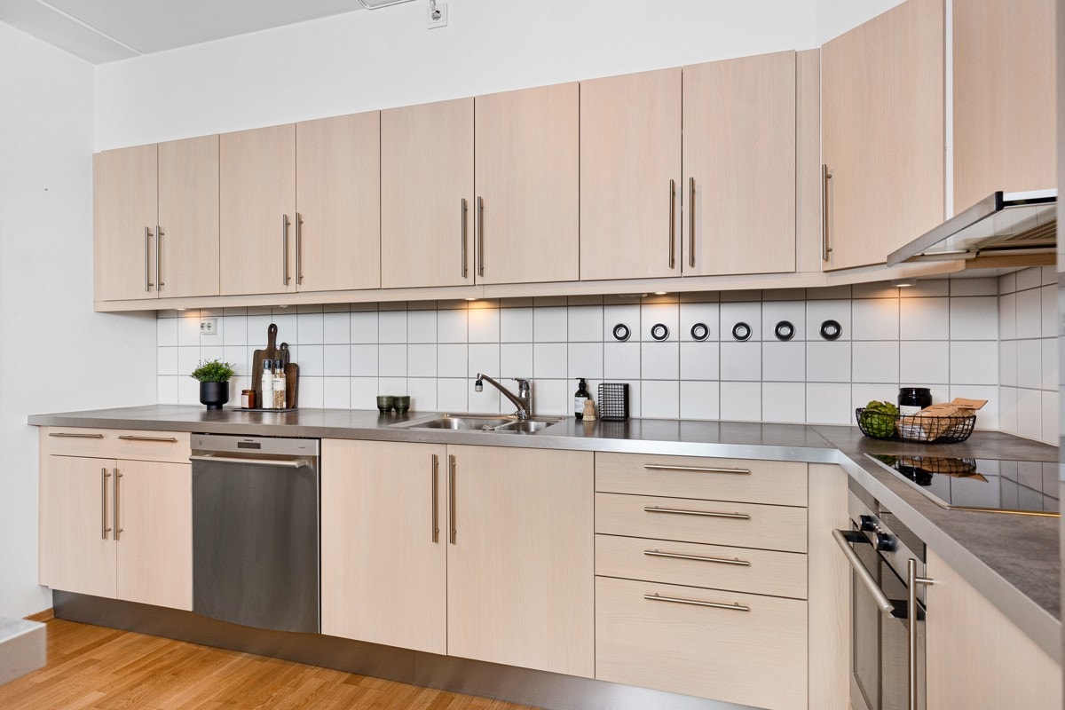 Kjøkkenet har benkebelysning, fliser over benk, integrert stekeovn og induksjonstopp Galleribilde