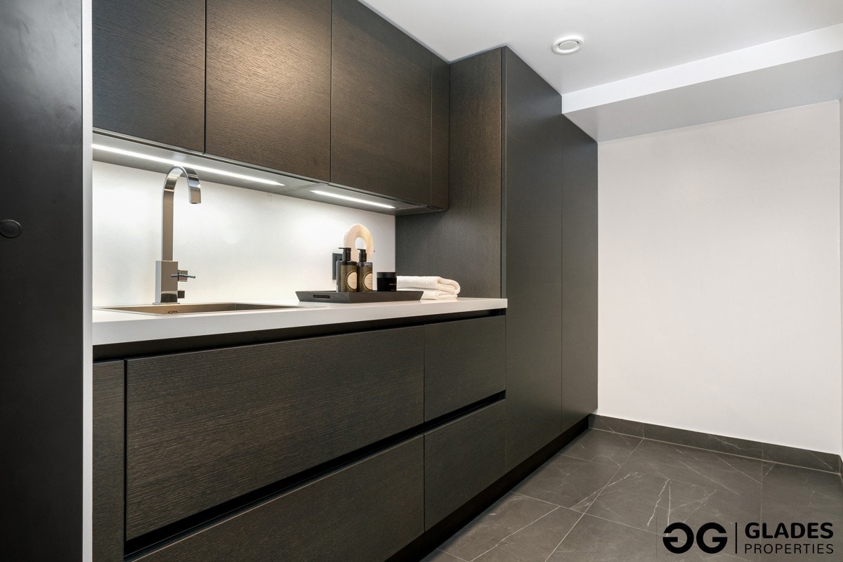 Vaskerommet ligger i kjelleren, like godt innredet som resten av huset. Rommet har 60 x 60 cm flis på gulv med sokkelflis, lysmalte vegger og en italiensk designinnredning i mørk eikefinér med skyllekum. Opplegg for vask/tørk i skap. Galleribilde