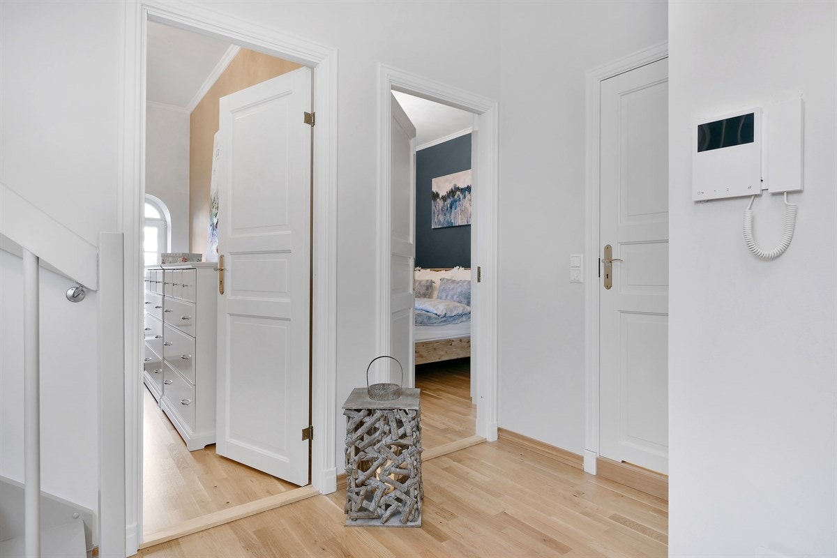 Entreen gir et pent inntrykk med trestavs eikeparkett, lyse vegger og en blå fondvegg som går helt opp til stuen i etasjen over. Galleribilde