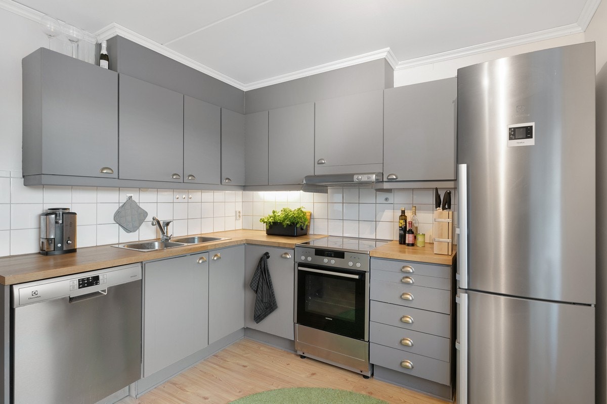 Kjøkkenet har fliser mellom under og overskap, og det er lagt laminatdekke på gulv Galleribilde