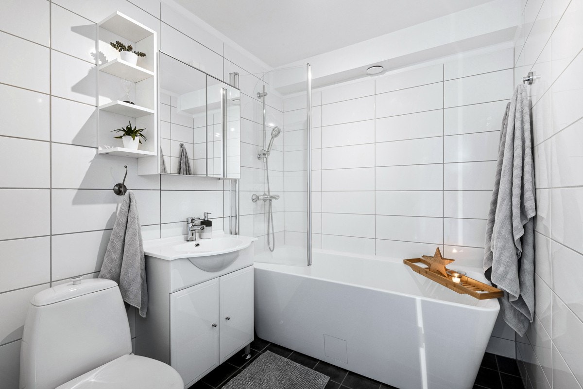Badet har mørke og hvite fliser på overflater, med varme i gulv. Galleribilde