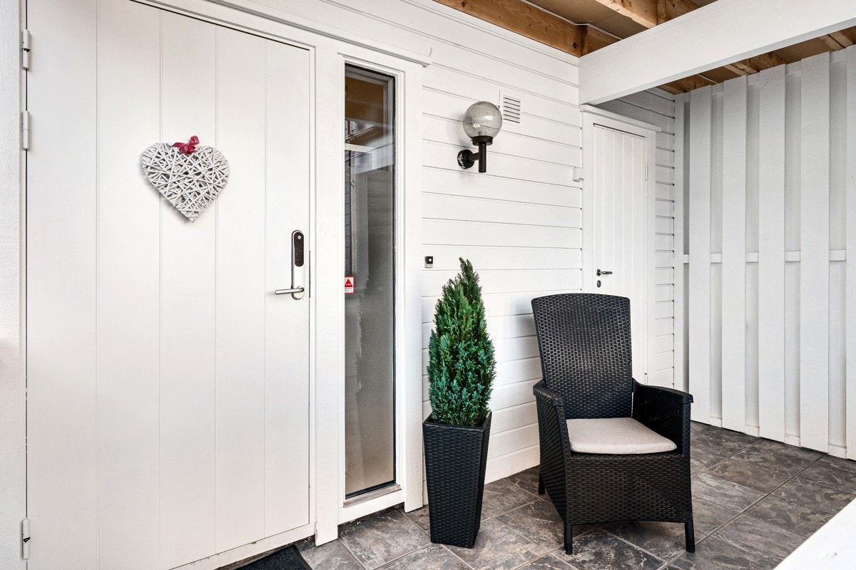 Inngangspartiet er overbygd, og en hvitmalt ytterdør med Yale doorman kodelås. Galleribilde