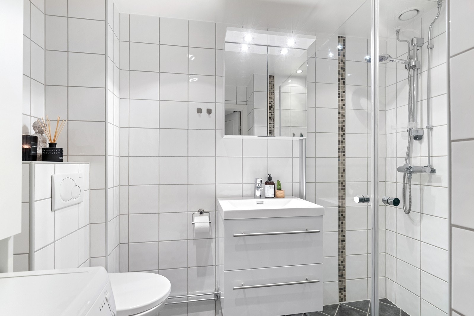 Bad/wc består av vegghengt wc, servant m/underskap, overskap m/speilfronter og overlys, dusjhjørne med glassdører Galleribilde