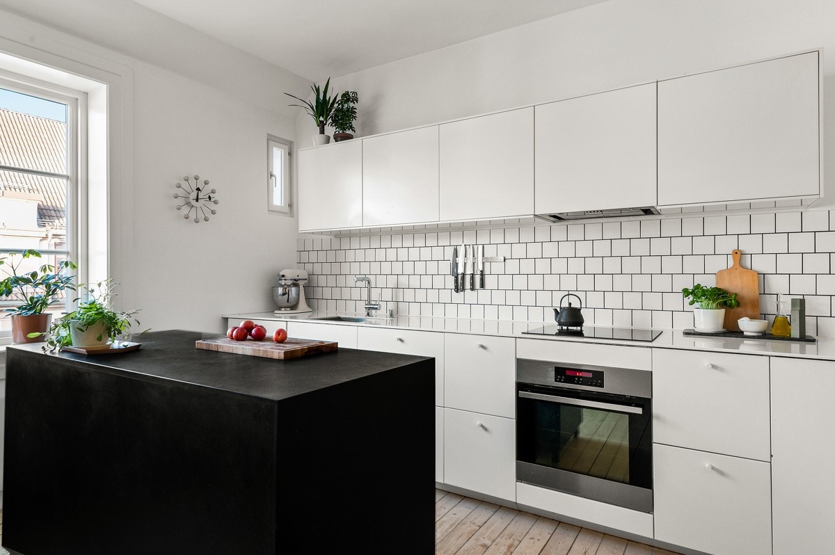 Moderne kjøkkeninnredning med hvite glatte fronter, stor arbeidsbenk og rikelig med skuffe- og skapplass. Galleribilde