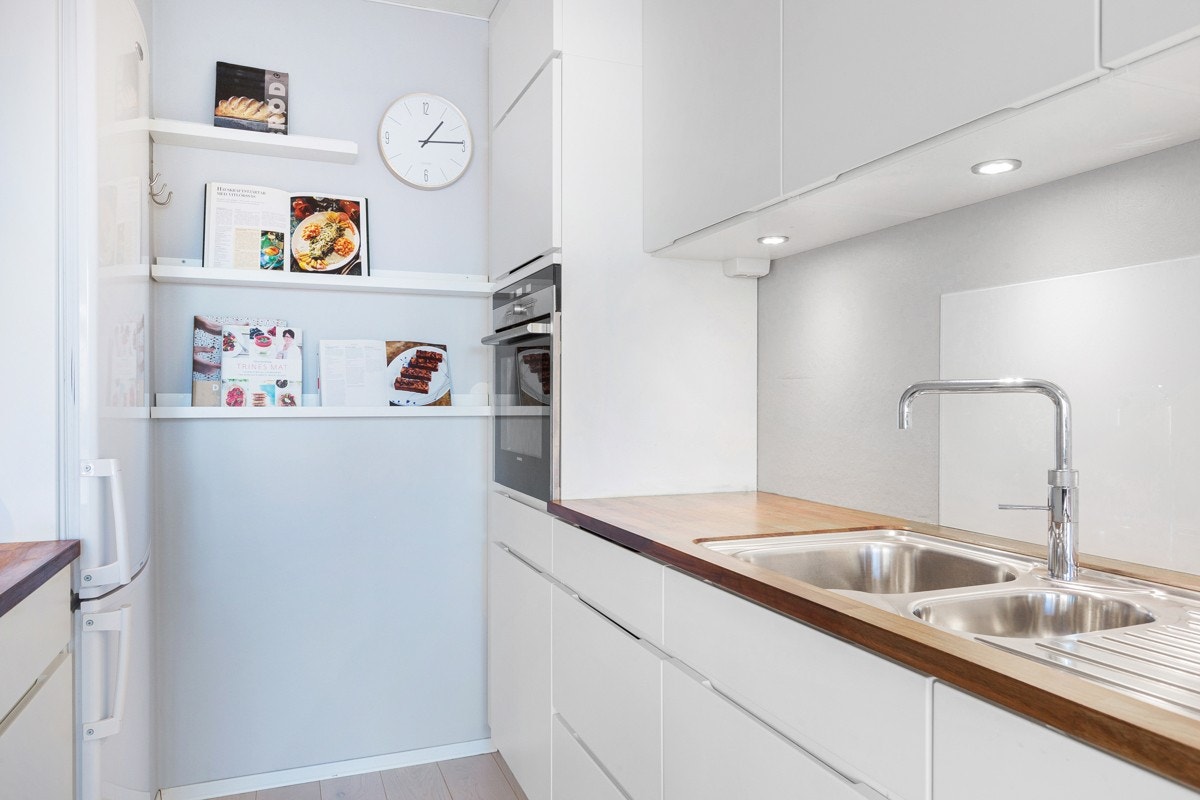 Kjøkkenet har håndtaksløse fronter, underlimt kum i heltre valnøtt benkeplate og benkebelysning. Praktisk ett-greps armatur med kokende vann fra Quooker. Galleribilde