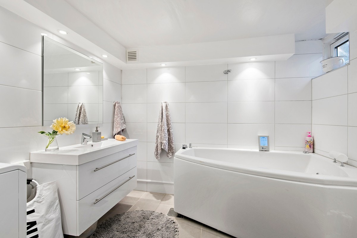 Flislagt bad i underetasjen med varmekabler i gulv, vegghengt wc og stort badekar Galleribilde