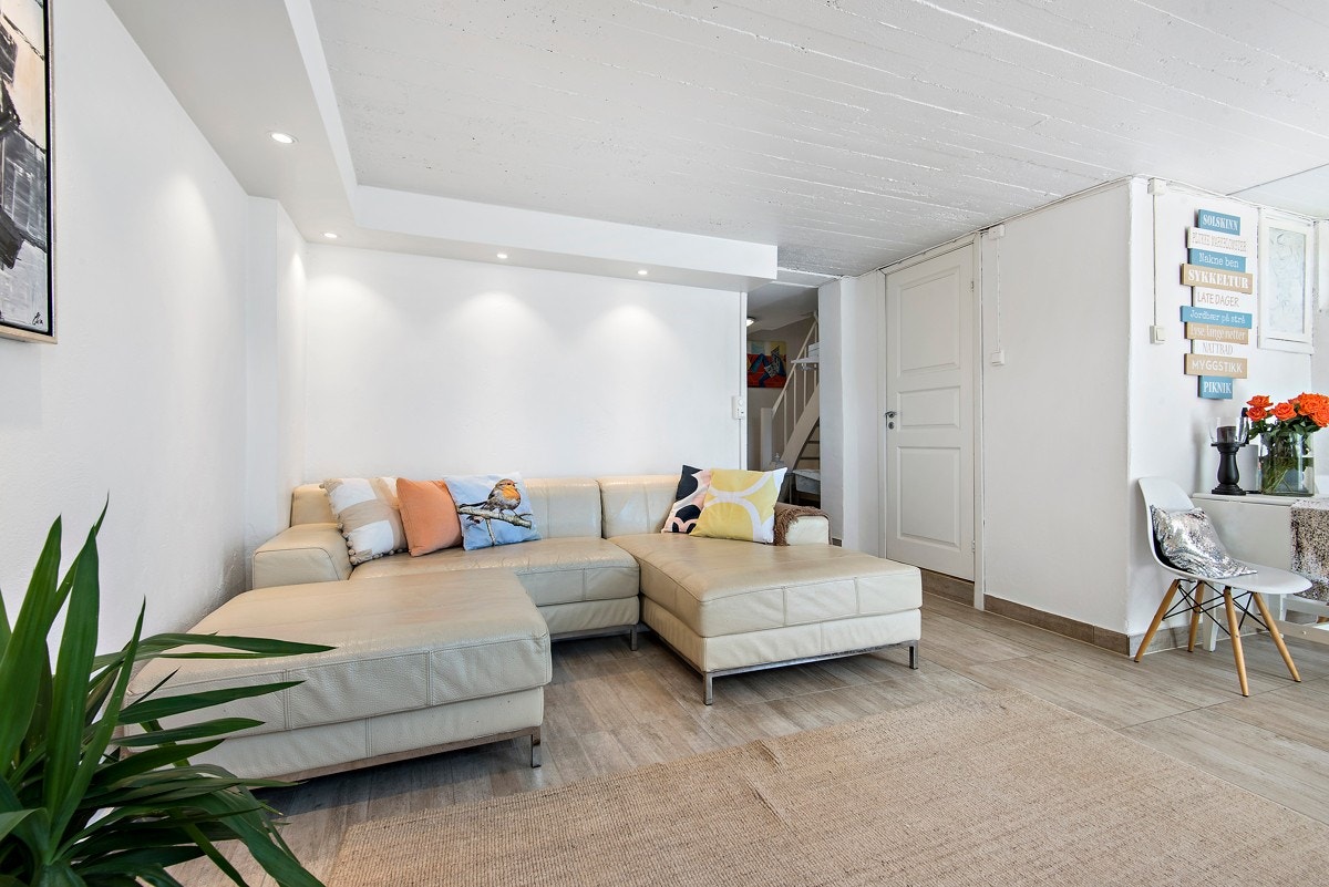 Stor kjellerstue i underetasjen med varme i gulv og utgang til terrasse med hage fra underetasjen Galleribilde