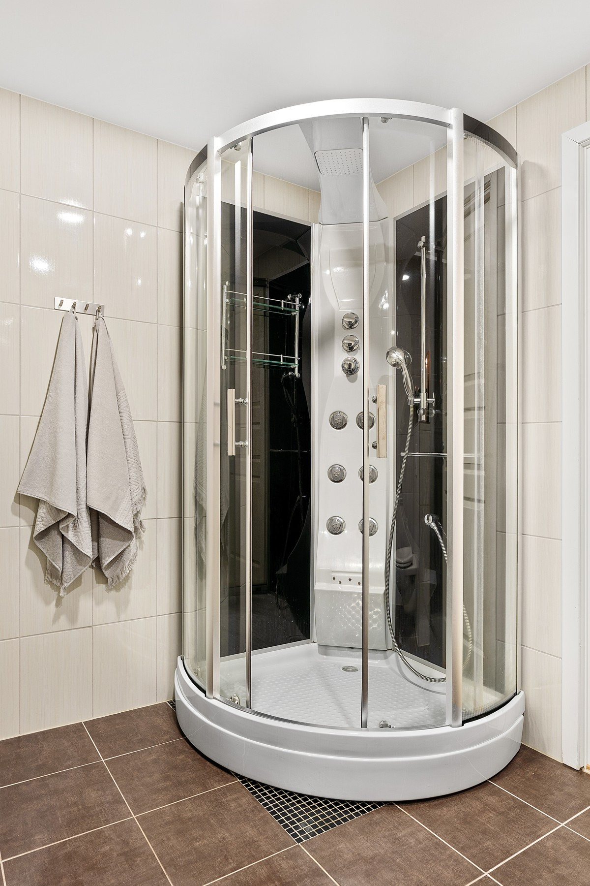 Badet er utstyrt med stort dusjkabinett, vegghengt wc, innredning med god skapplass, samt kran og avløp for vaskemaskin.
