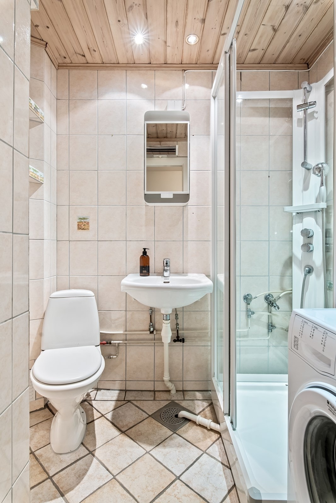 Flislagt bad med dusjkabinett, toalett, servant og speilskap. Galleribilde