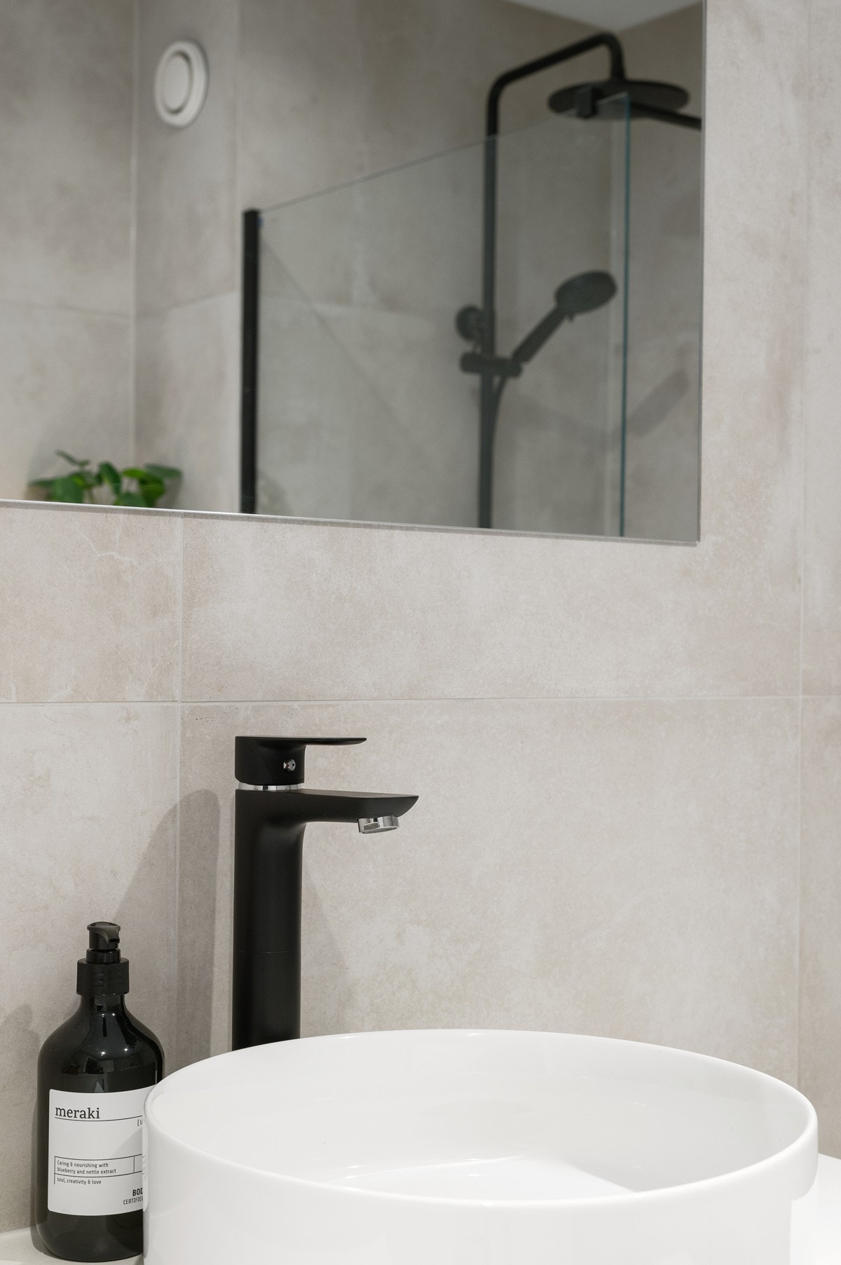 Badet har tidløse beige overflater og moderne innredning med sorte detaljer Galleribilde