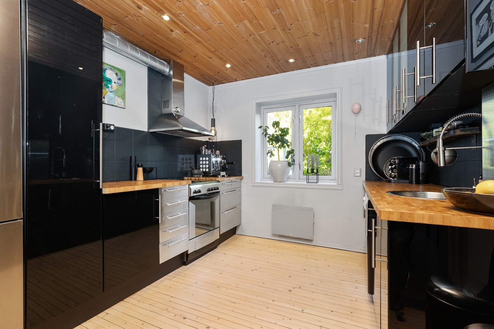 Kjøkkenet har Ikea sort høyglans fronter og stålfronter. Benkeplate i tre og malte fliser over benk. Galleribilde