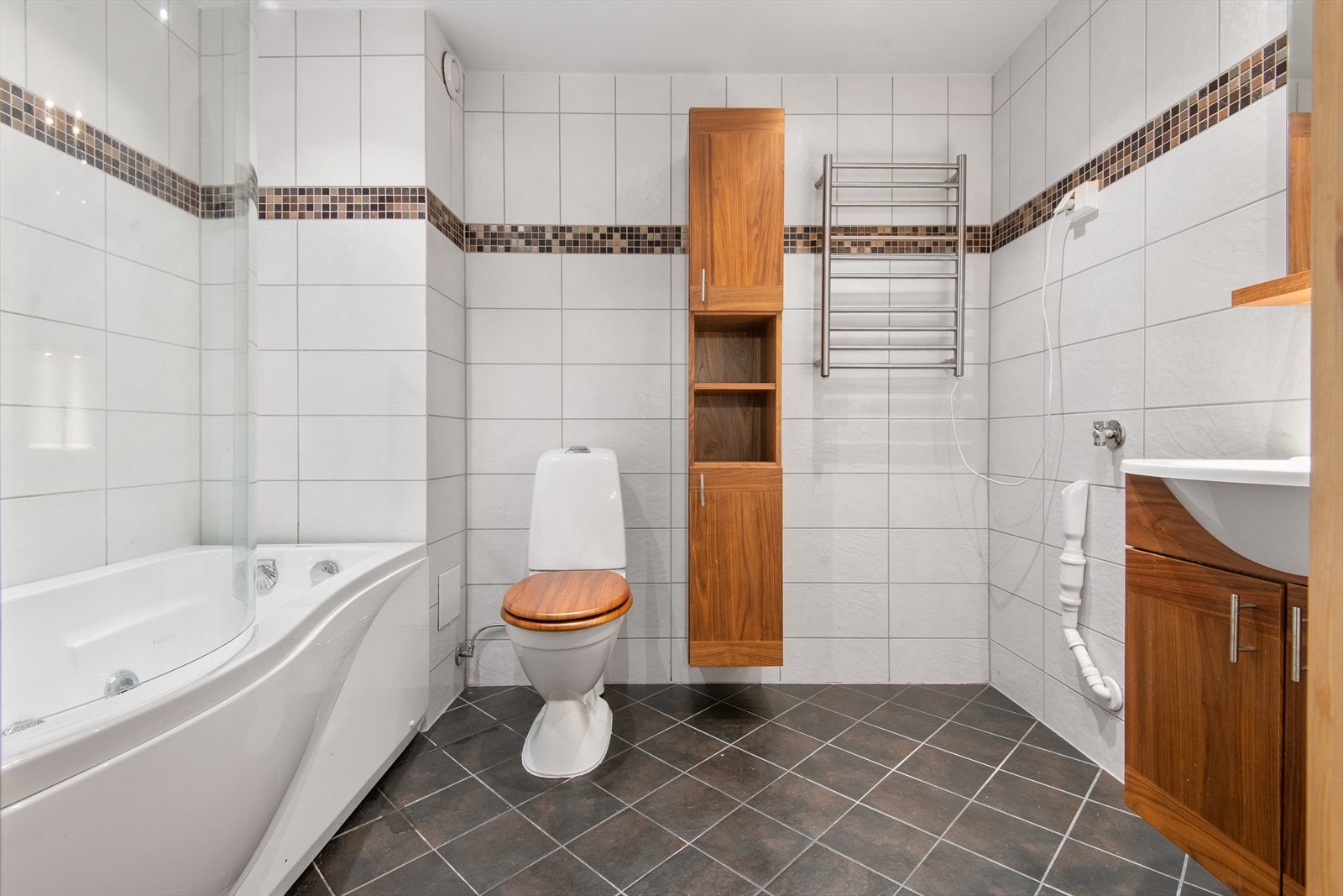 Innredningen består av heldekkende servant over underskap, speil med lysarmatur, toalett, håndkletørker og boblekar med både vann og luftdyser. Galleribilde