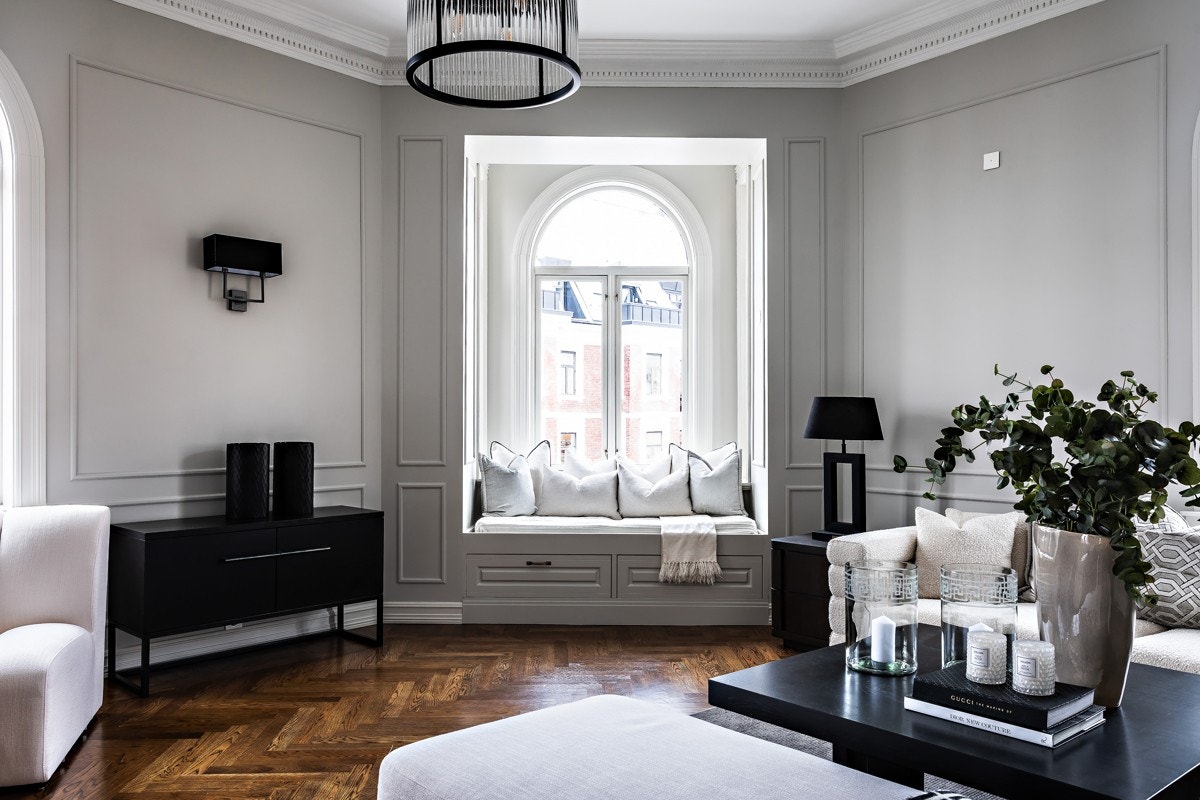 Stuen i hjørnet av leiligheten er pen og elegant. Rommet har store vinduer som slipper inn rikelig med dagslys og i hjørnevinduet er det en plassbygget daybed med skuffeløsning under. Galleribilde