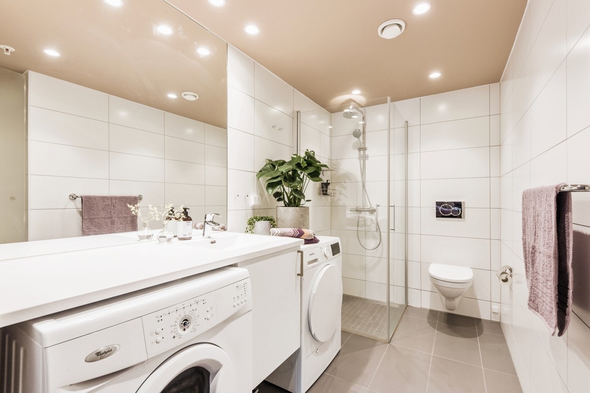 Stort flislagt baderom med downlights, tørkeskap, gulvvarme, dusjnisje i glass samt opplegg og plass til både vaskemaskin og tørketrommel. Galleribilde