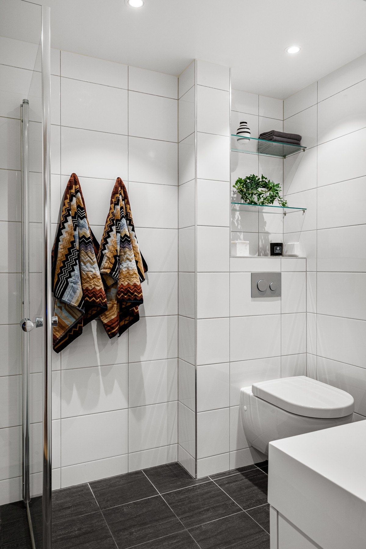 Badet er flislagt med gulvvarme og det er praktisk med glasshyller i nisje over den innebygde sisternen. Galleribilde