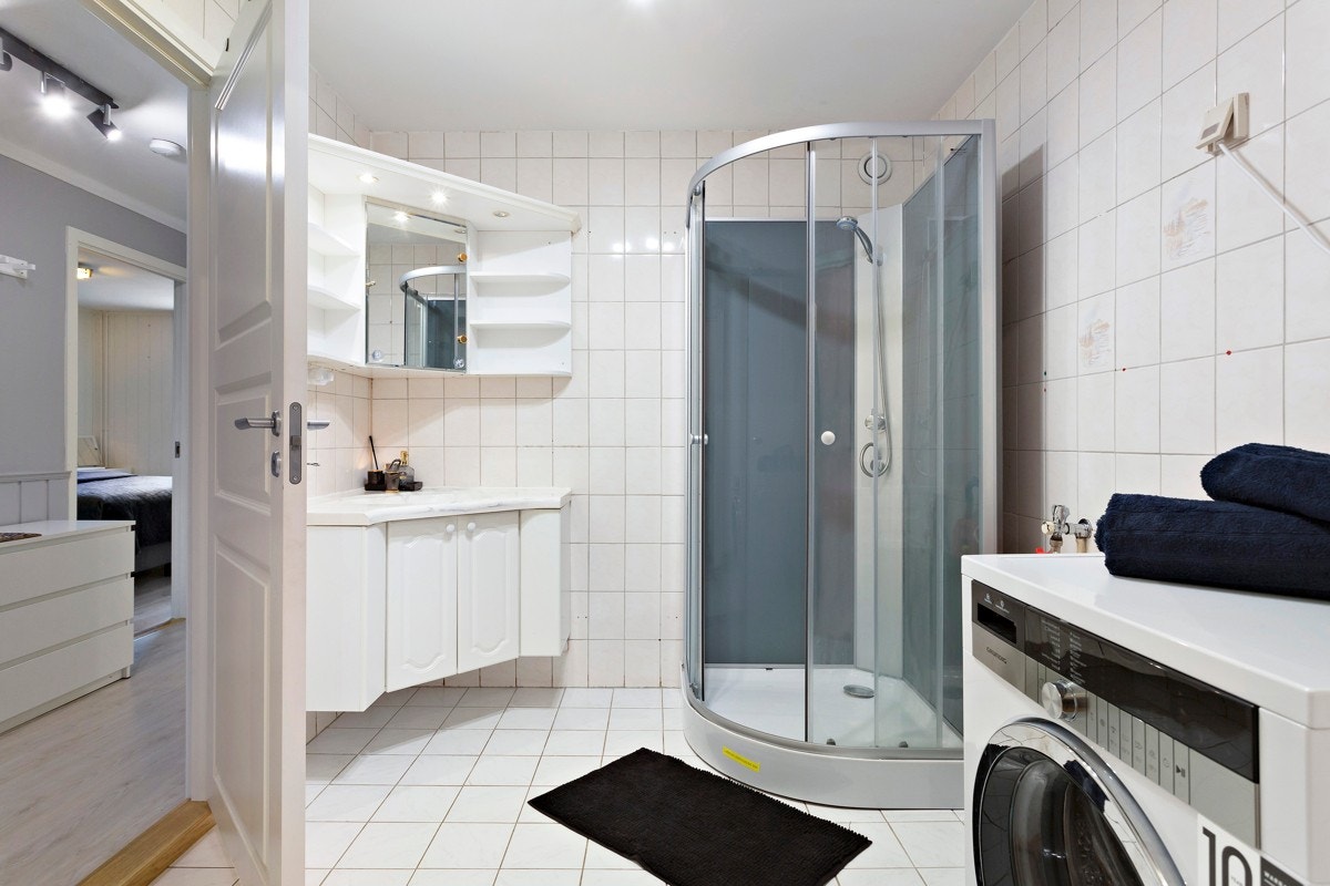 Romslig flislagt baderom med opplegg til vaskemaskin Galleribilde