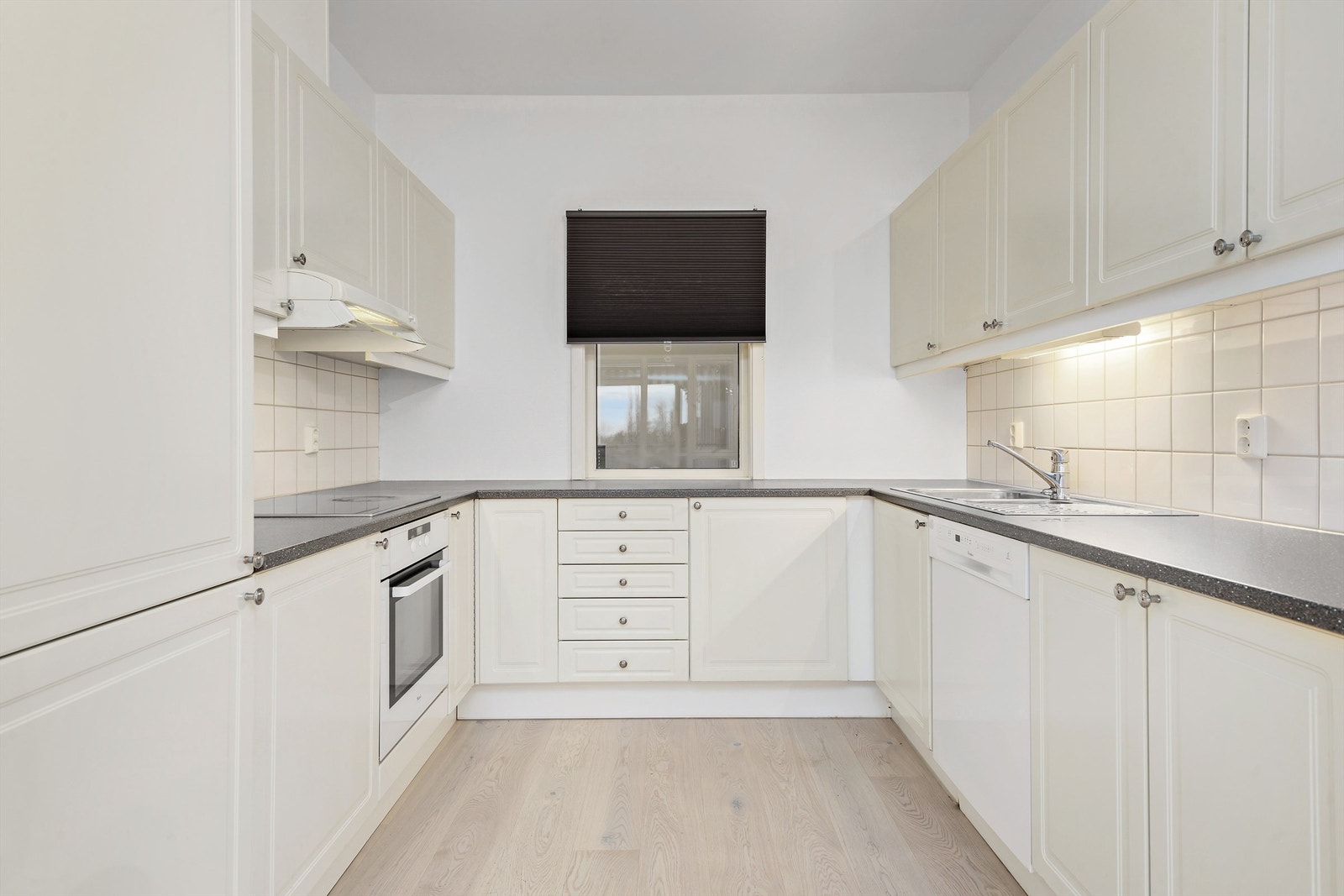 Lyst kjøkken praktiski hestesko. Kjøkkenet har integrerte hvitevarer og godt med både skap og benkeplass. Galleribilde