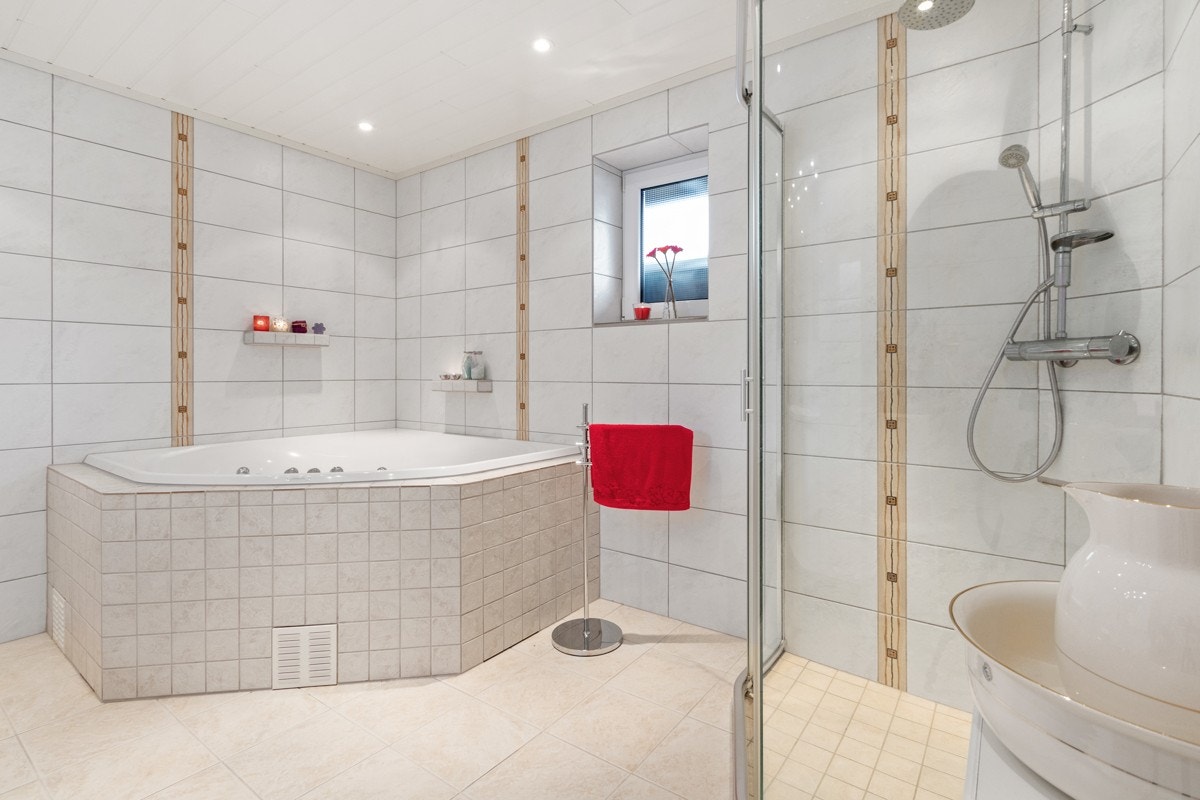 Baderom 1. etg. med dusjkabinett, hjørnebadekar, vegghengt toalett og lys baderomsinnredning med vask Galleribilde