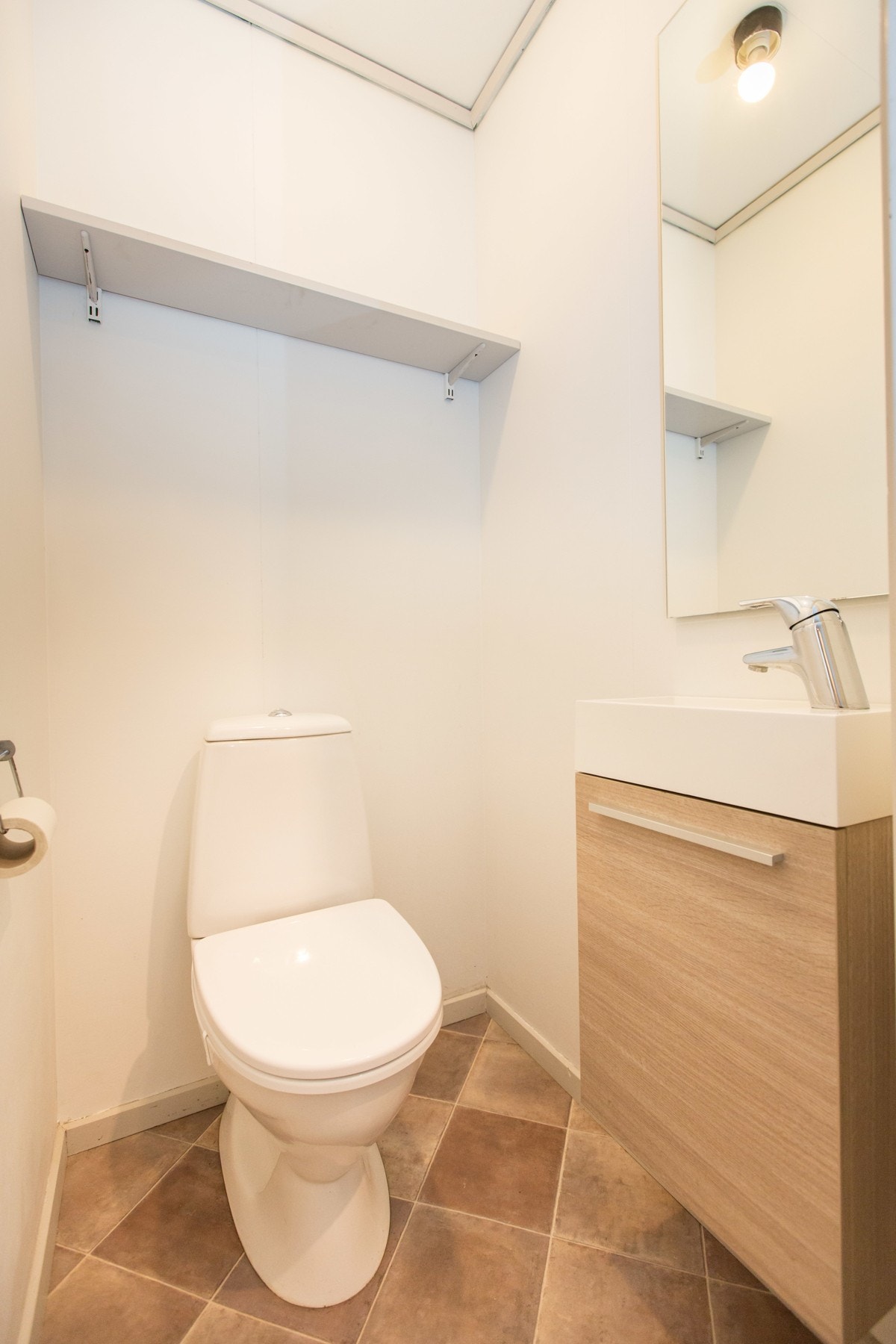 Ved siden av badet i gangen finner en også et egen toalettrom. Toalettrommet er innredet med en liten og praktisk servant med underskap, hylle samt frittstående toalett. Galleribilde