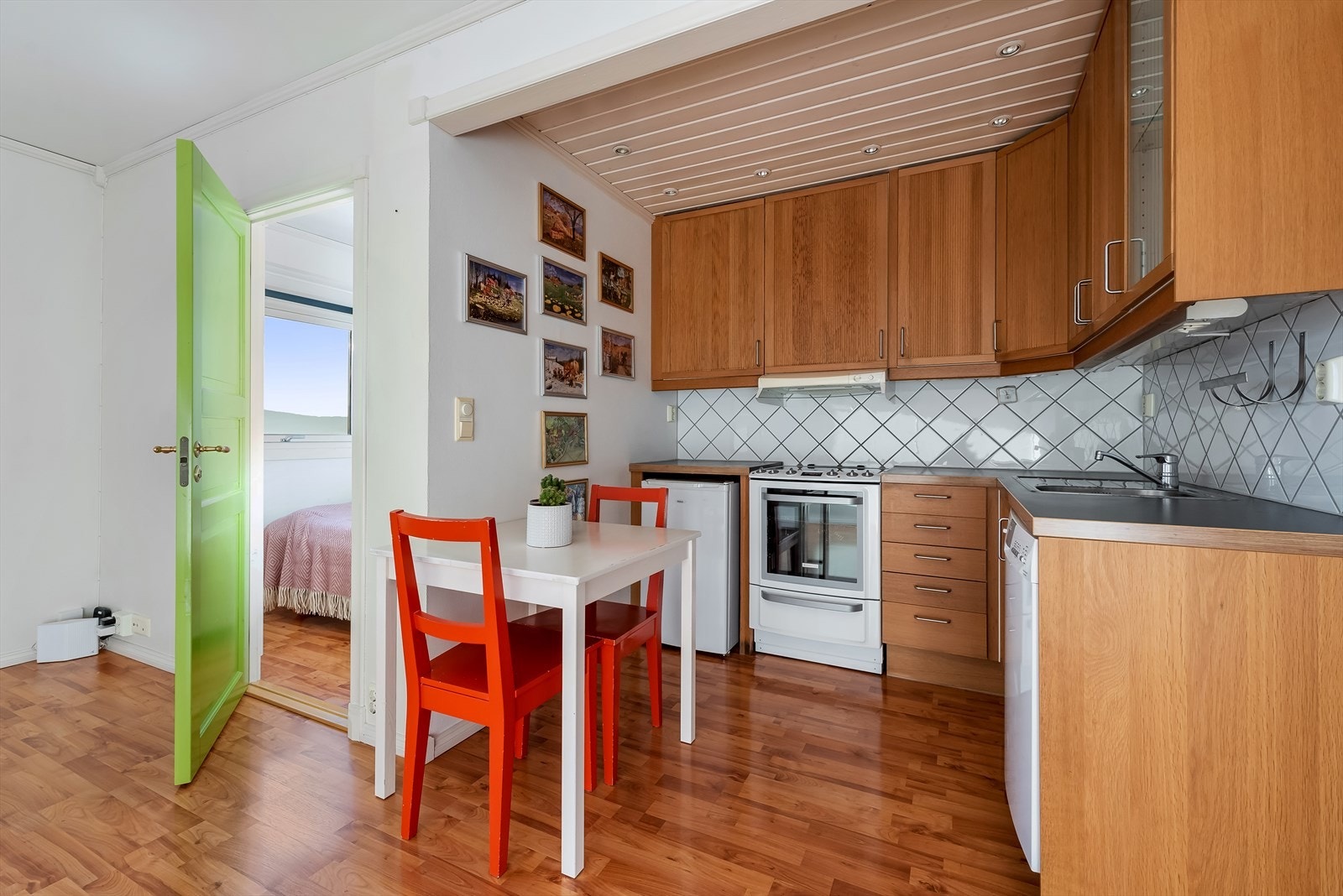 Praktisk kjøkkenløsning med profilerte fronter samt en glassfront, benkeplate i laminat og nedfelt kum med ett-greps blandebatteri. Galleribilde