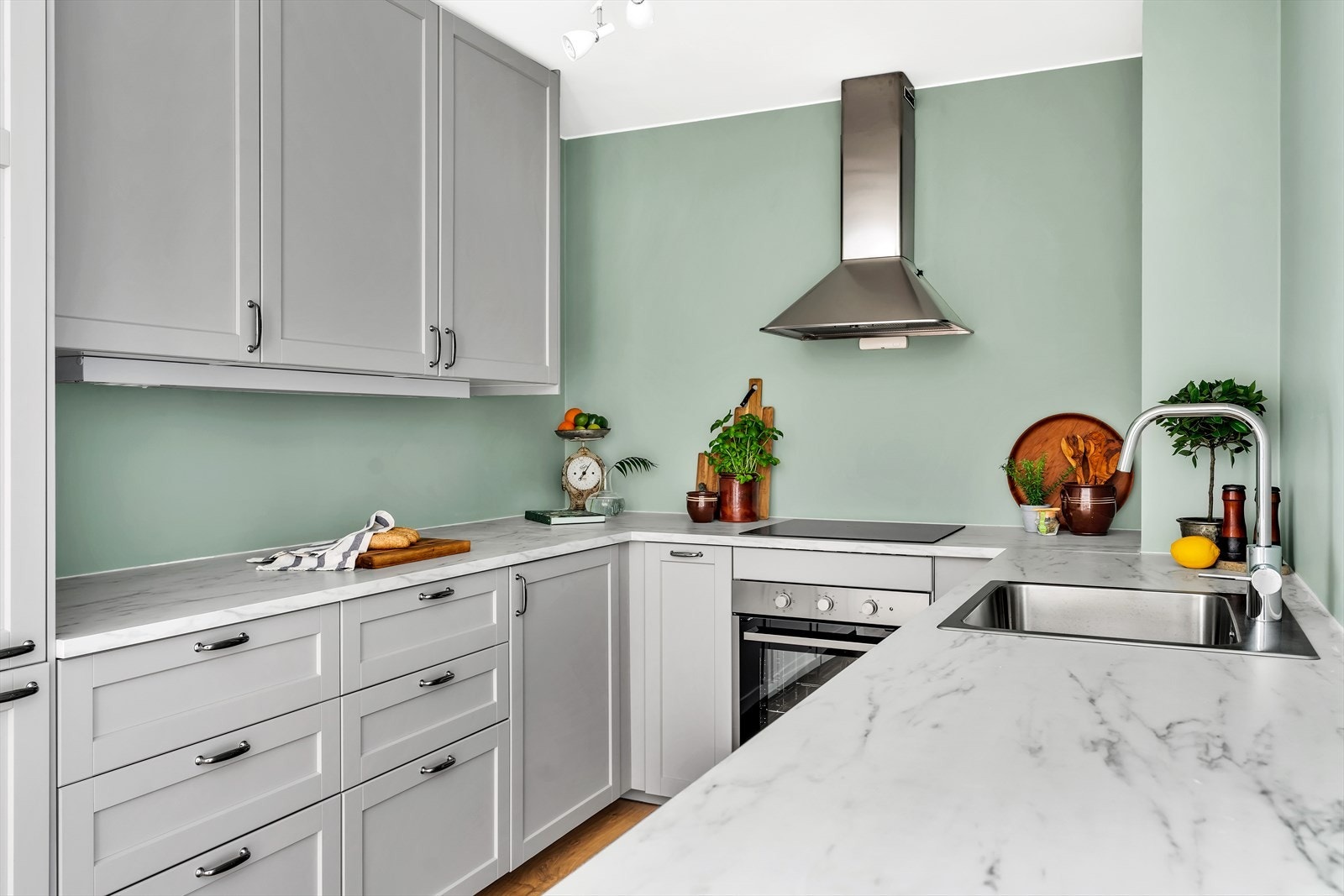 Grå innredning fra IKEA med profilerte fronter, laminert benkeplate og nedfelt oppvaskkum. Galleribilde